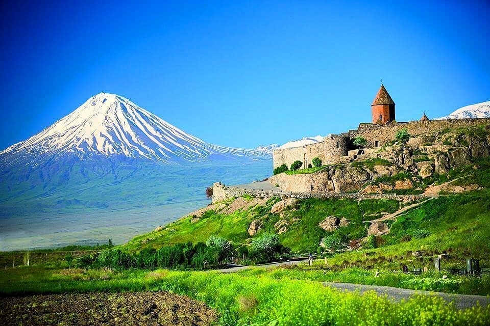 山坡上的石造修道院，遠方有白雪覆蓋的山峰。
