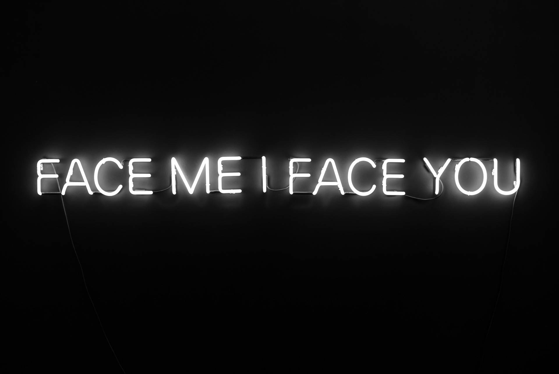 黑色牆上寫著 face me i face you 的白色霓虹燈牌