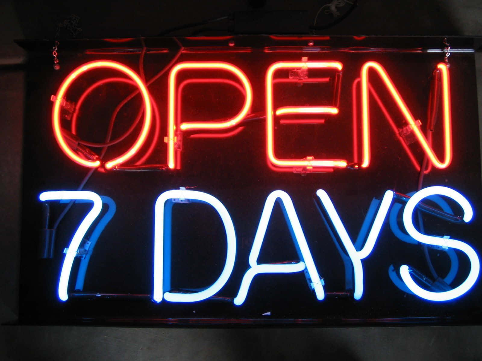 霓虹燈牌發出紅藍光芒，寫著「OPEN 7 DAYS」
