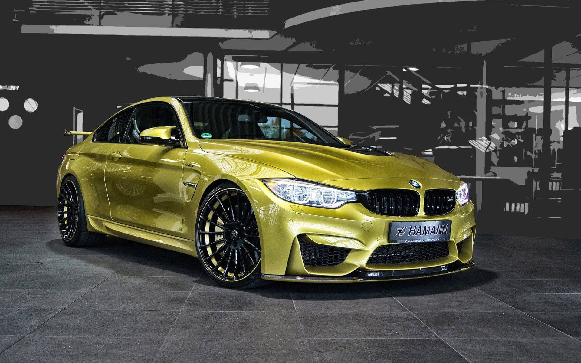 霓虹BMW M系列跑車 壁紙 — 一輛閃耀金色的Hamann改裝BMW M4轎跑車，在簡約工業風車庫中展示，背景為單色調。