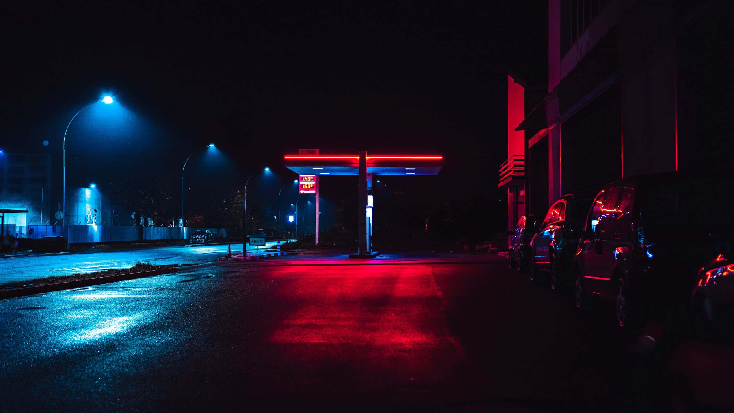 夜晚霓虹加油站，紅色和藍色燈光在濕路面上。