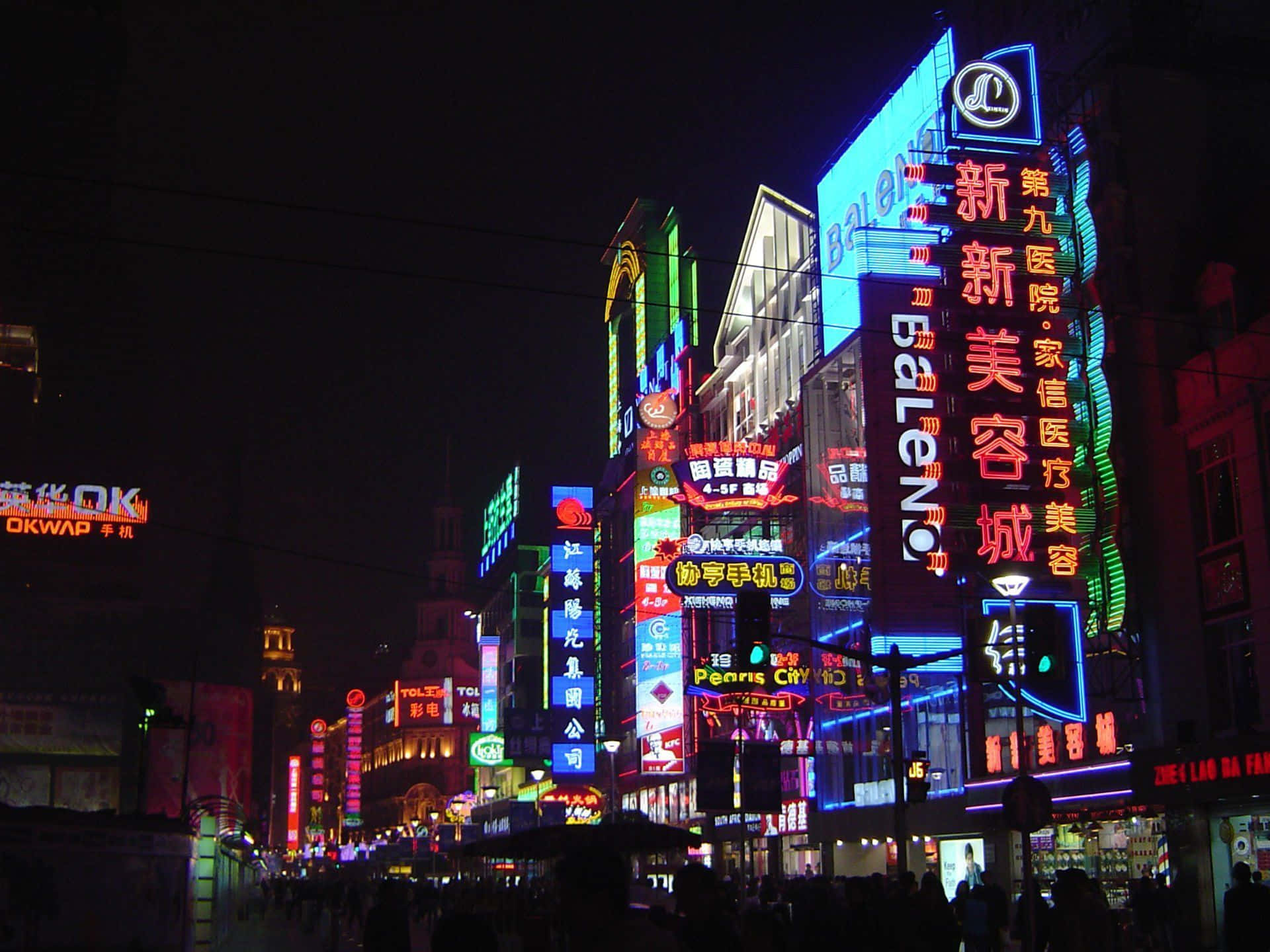 霓虹城市夜生活圖 壁紙 — 充滿活力的霓虹燈招牌照亮了夜晚繁忙的城市街道，下方有發光的廣告和人群。