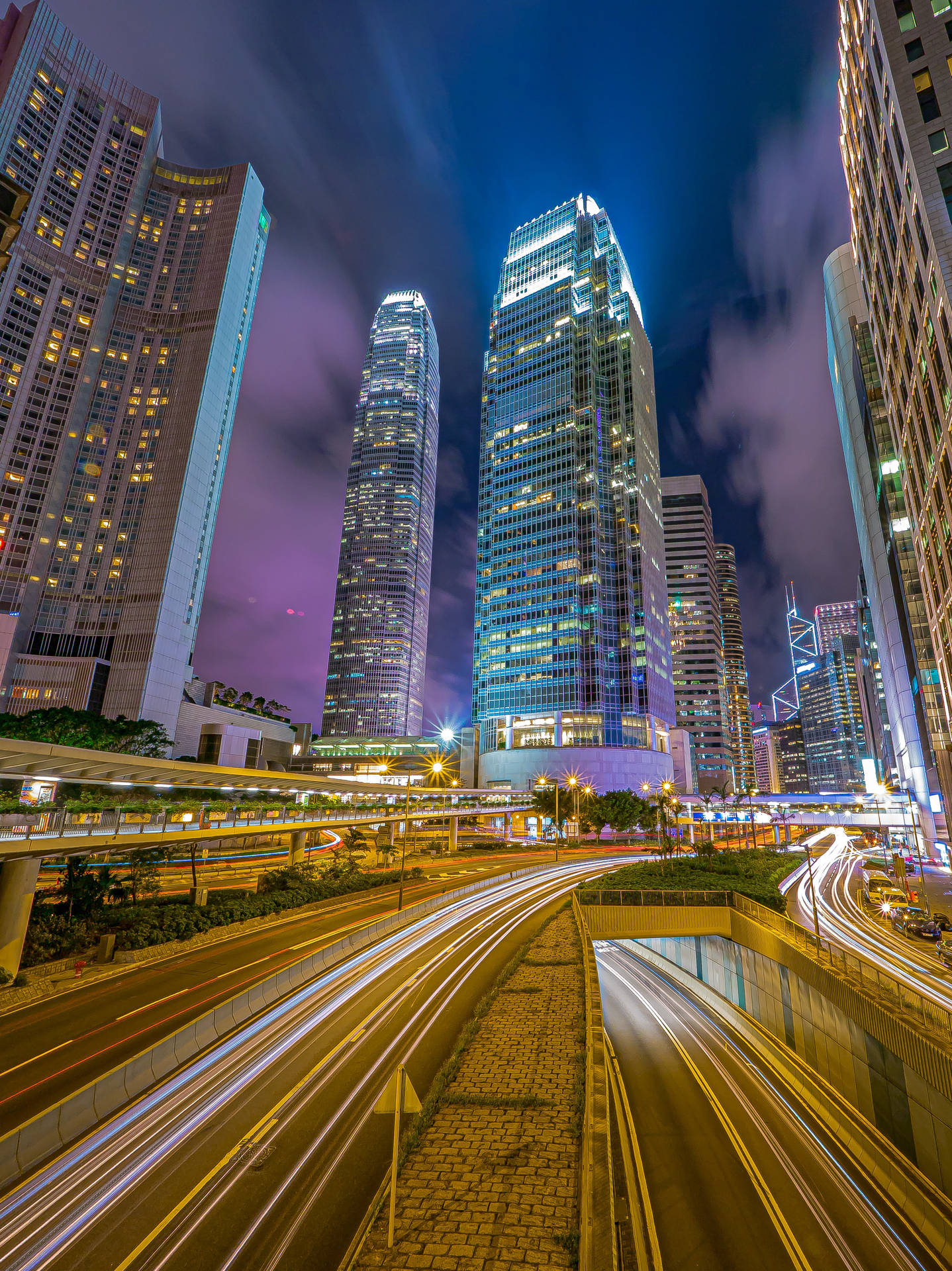 夜間城市場景，有燈火通明的摩天大樓和流動的車燈。