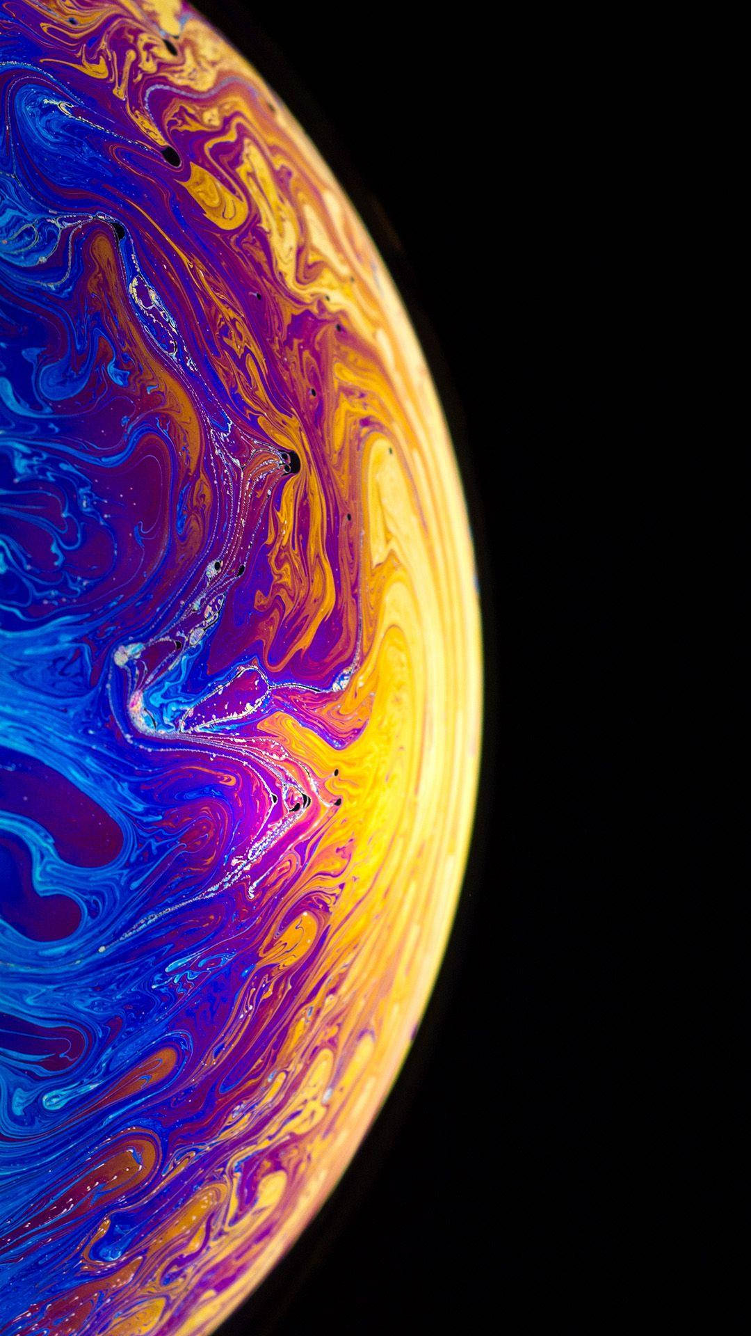 霓虹星球 iPhone 活動壁紙 壁紙 — 一個在漆黑虛空中旋轉的宇宙球體，帶有電光藍、紫色和金色。