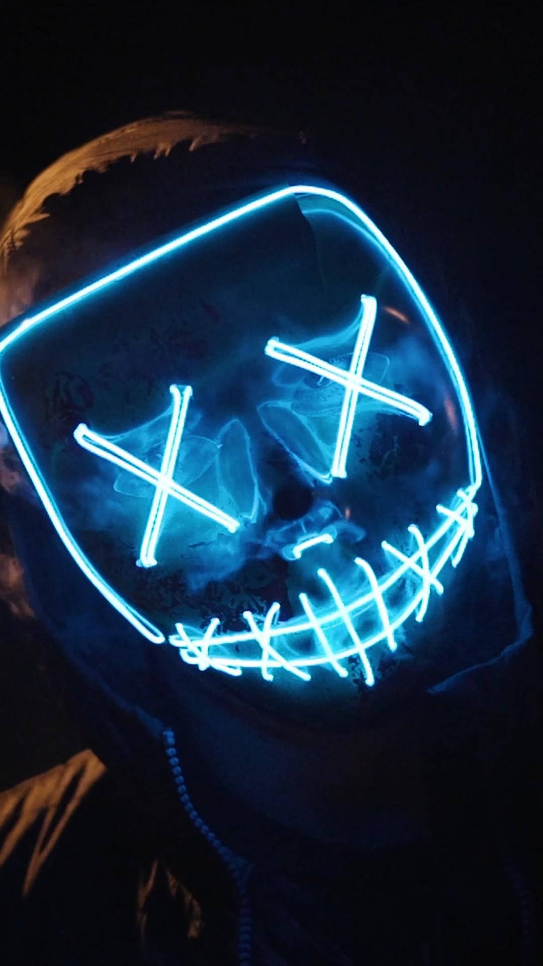 霓虹燈光Marshmello iPhone壁紙 壁紙 — 一個人戴著發光藍色LED面具，有X眼睛和縫合嘴巴，背景為深色。