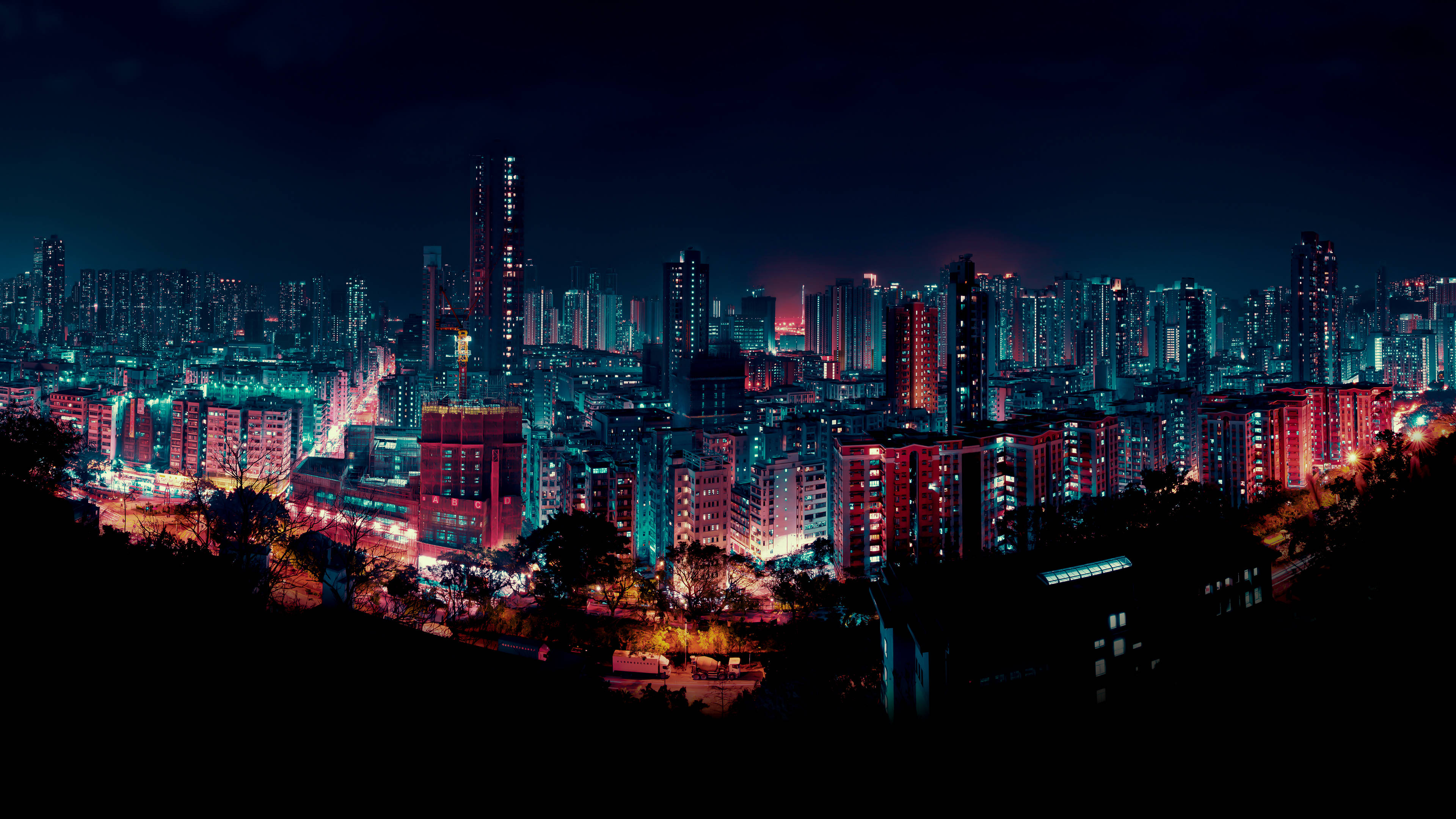 霓虹燈光城市夜景 壁紙 — 廣闊的城市夜景，高聳的摩天大樓和住宅建築在黑暗的天空下閃耀著鮮豔的紅色和藍色。