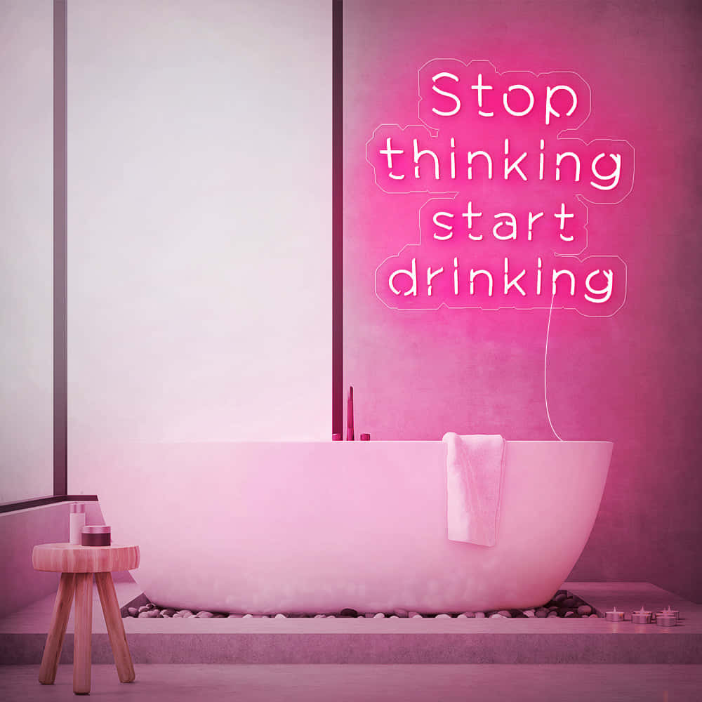 浴室內的粉紅色霓虹燈牌在浴缸上方顯示「Stop thinking start drinking」。