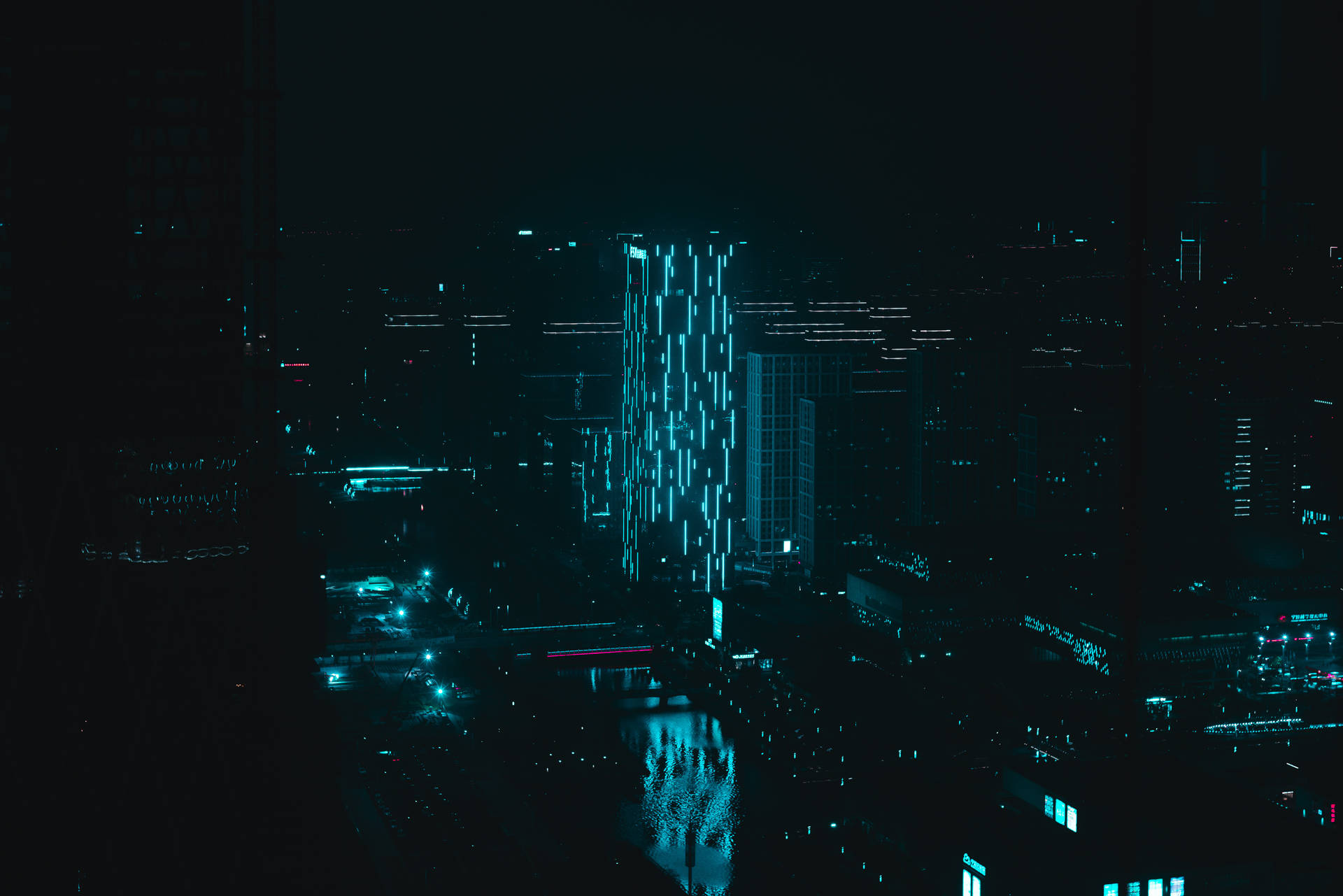 夜晚的黑暗城市，有一座發光的藍色摩天大樓和水面上的倒影。