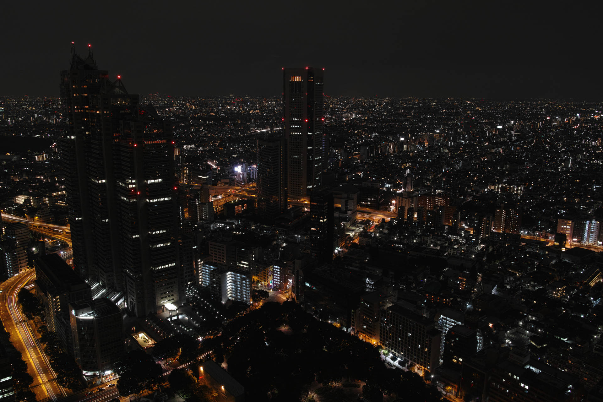 密集城市區域的夜間空中照片，建築物和道路燈火通明。
