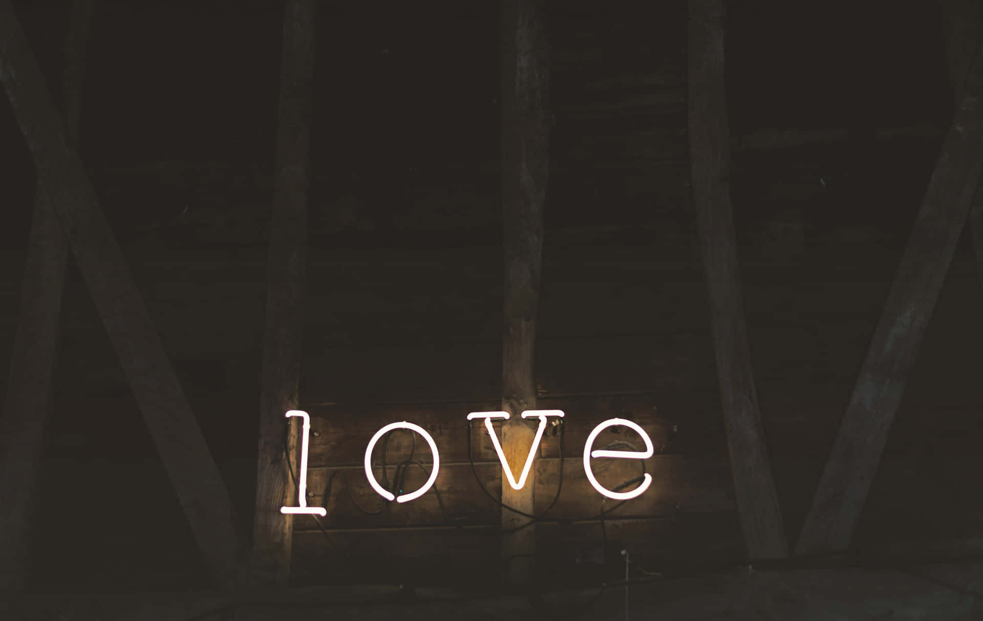 在深色木質閣樓空間中發光的霓虹 love 標誌。