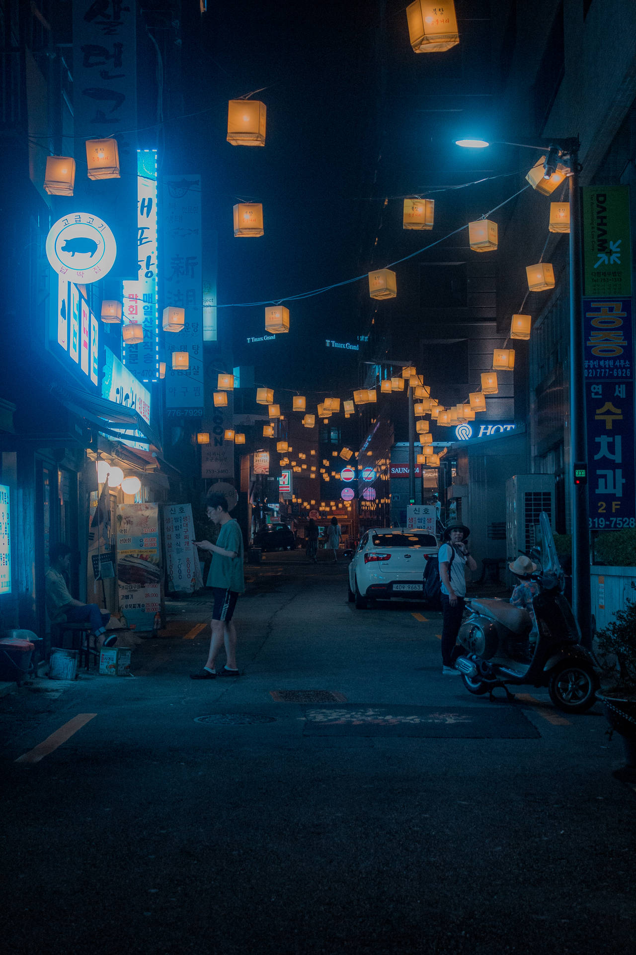 韓國城市小巷中，有發光燈籠和霓虹招牌的夜晚街景。