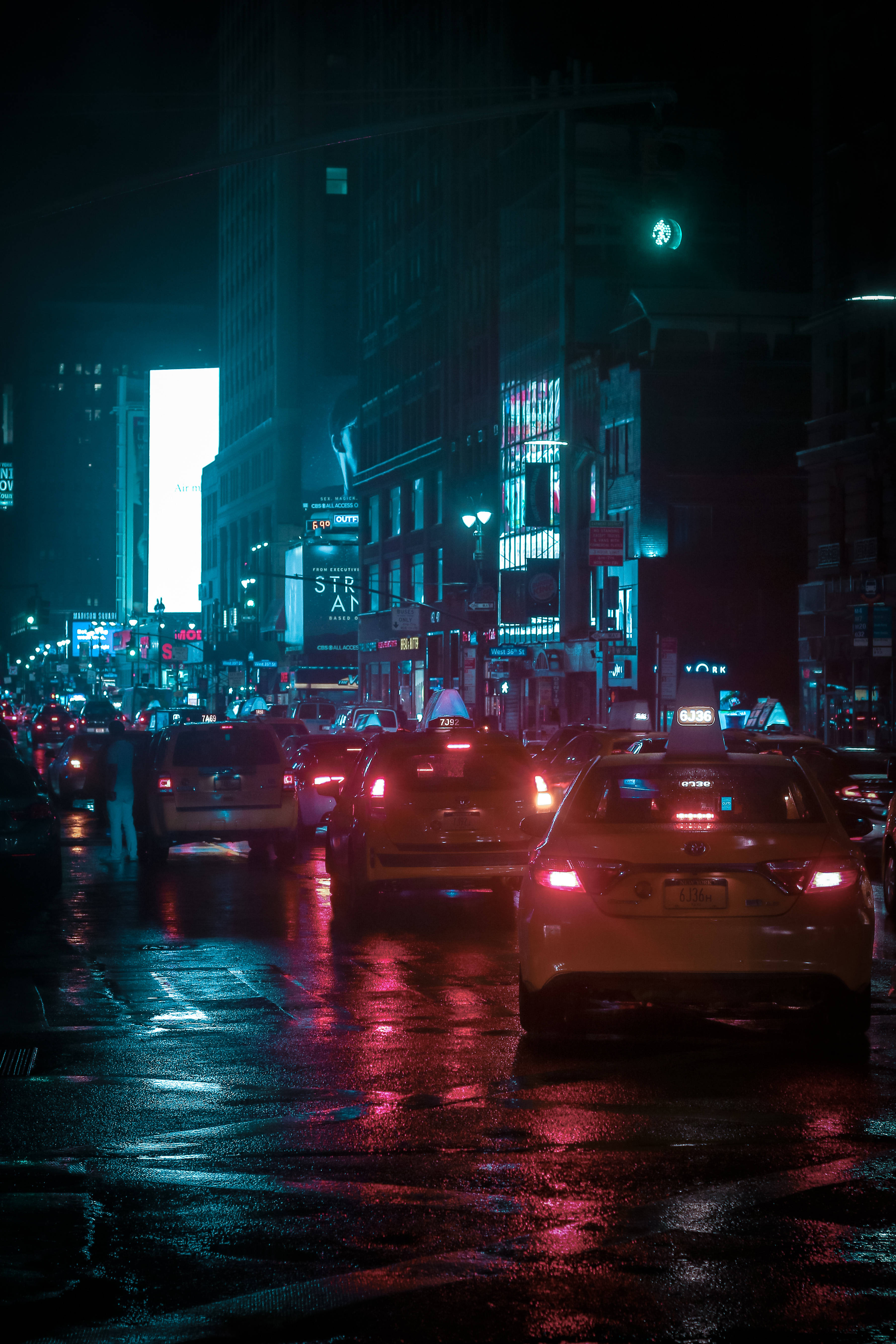 霓虹燈裝飾的繁忙街頭汽車 壁紙 — 一條雨夜的城市街道，霓虹燈光在濕漉漉的路面上閃爍，汽車駛過。