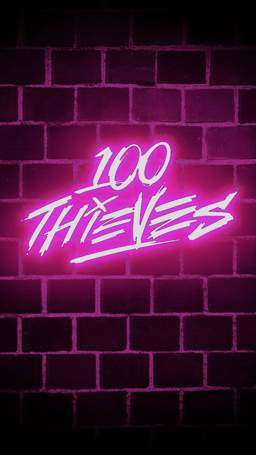 黑暗磚牆上寫著 100 THIEVES 的粉紅色霓虹燈招牌。