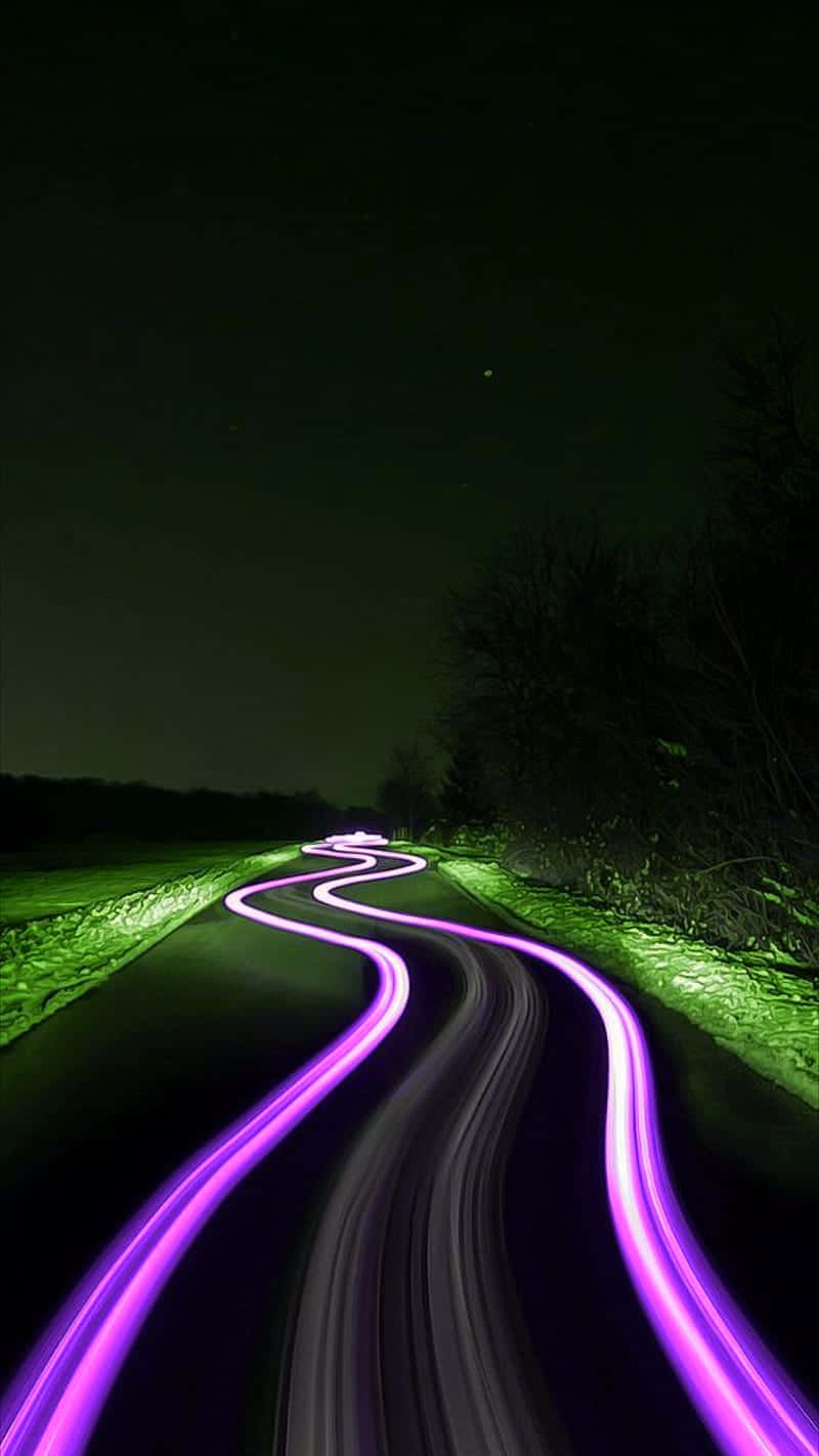 夜晚的蜿蜒道路，帶有紫色光軌和發光的綠色邊緣。