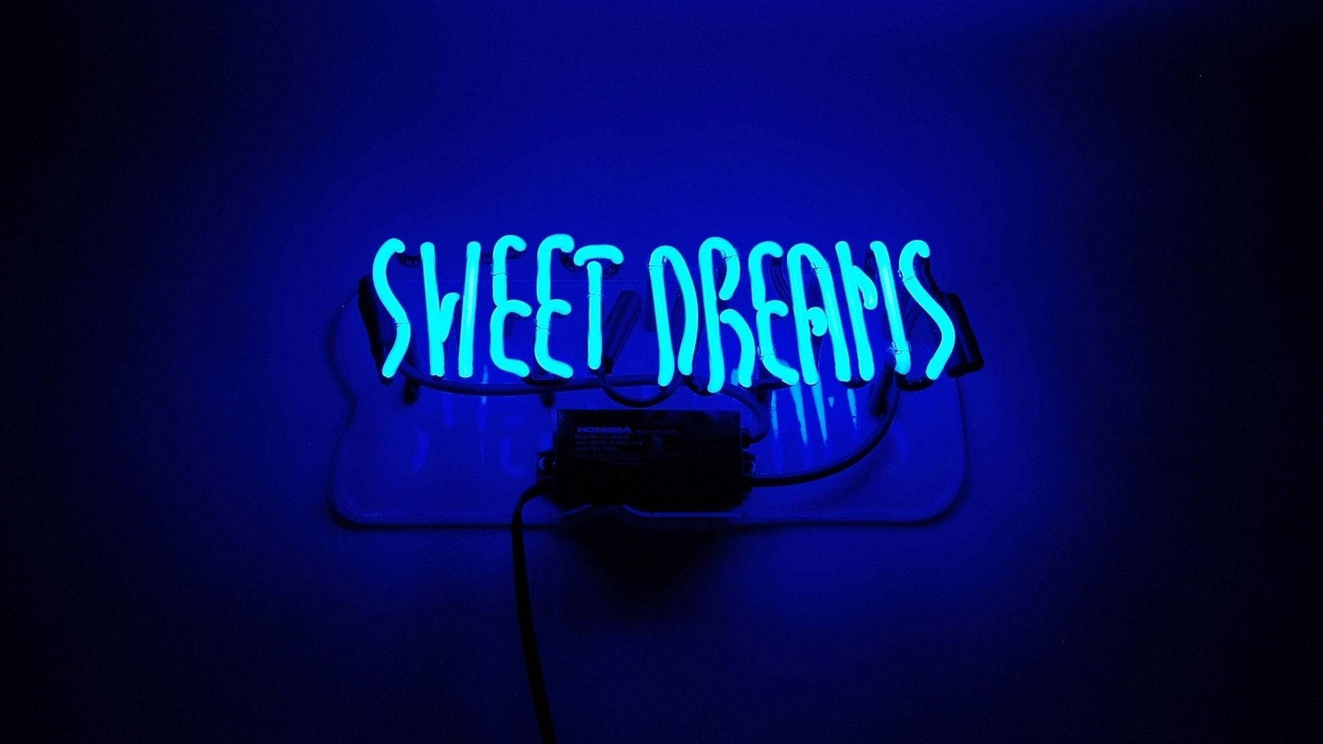 深色牆壁上寫著 sweet dreams 的藍色霓虹燈牌。