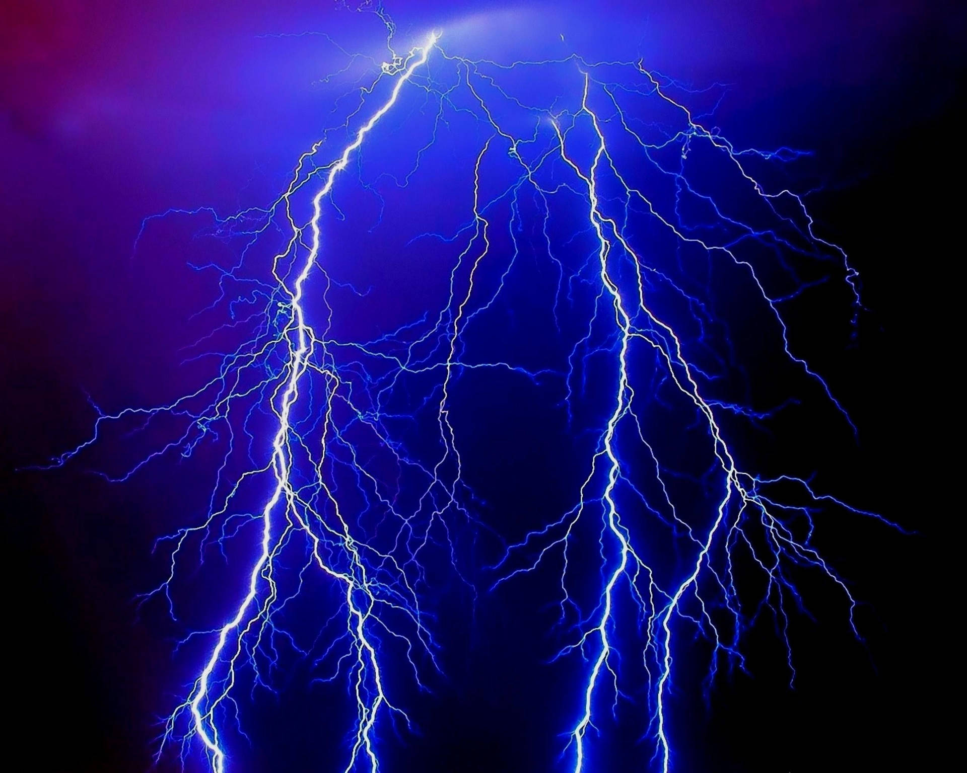 強烈的藍色閃電照亮了帶有紫色色調的黑暗暴風雨天空。