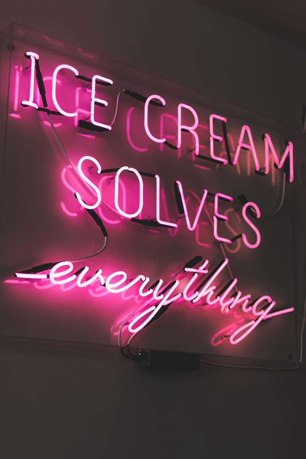 黑暗牆上寫著 ice cream solves everything 的粉紅色霓虹燈牌。