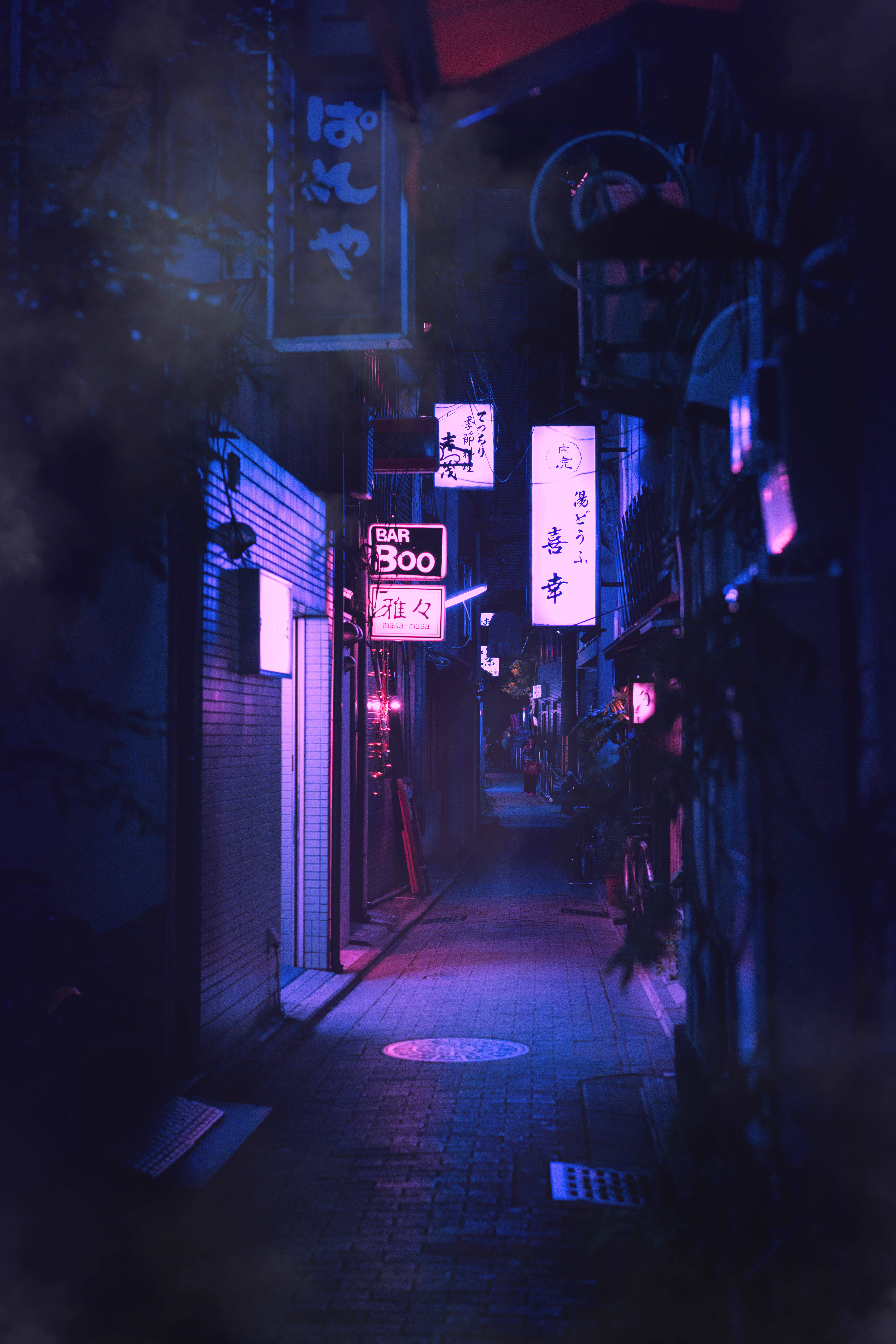 霓虹風格巷弄iPhone背景 壁紙 — 日本城市夜晚一條狹窄的霓虹燈小巷，發光的招牌在潮濕的路面上投射出紫色和藍色的色調。