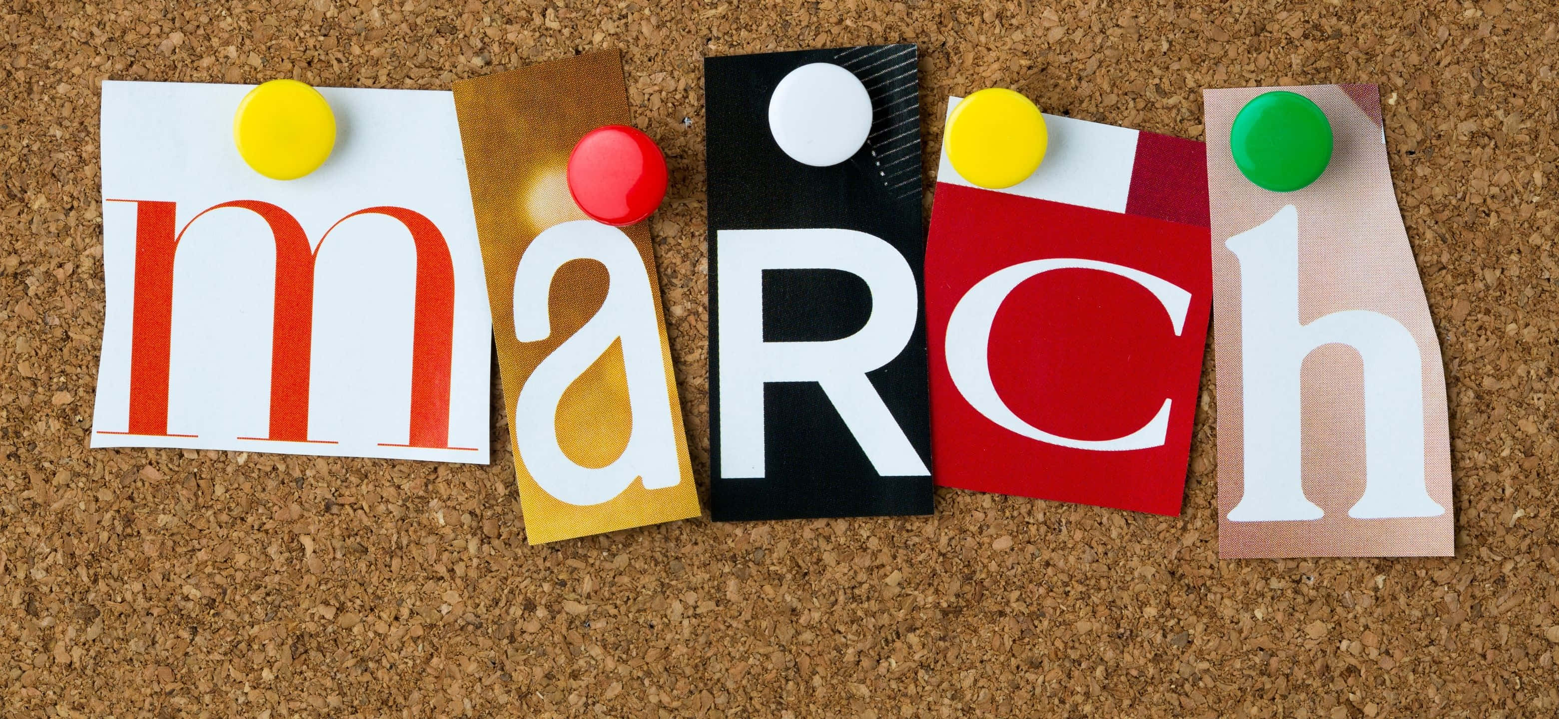 霜凍冬晨小鎮風光 壁紙 — 「March」呢個字用色彩繽紛嘅剪出字母，用鮮艷嘅圖釘釘喺軟木板上。