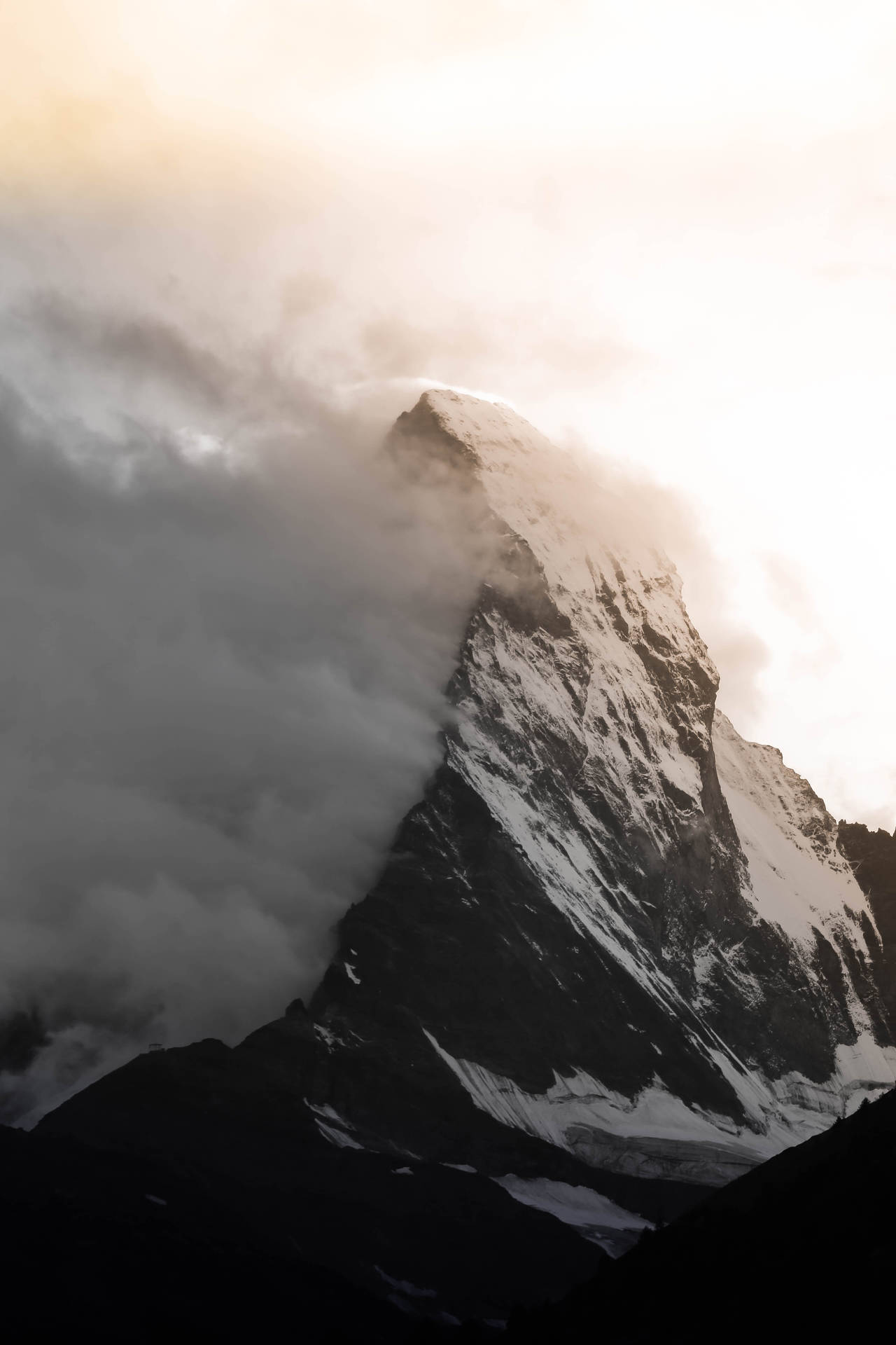 白雪覆蓋的山峰從日出時的雲層中浮現