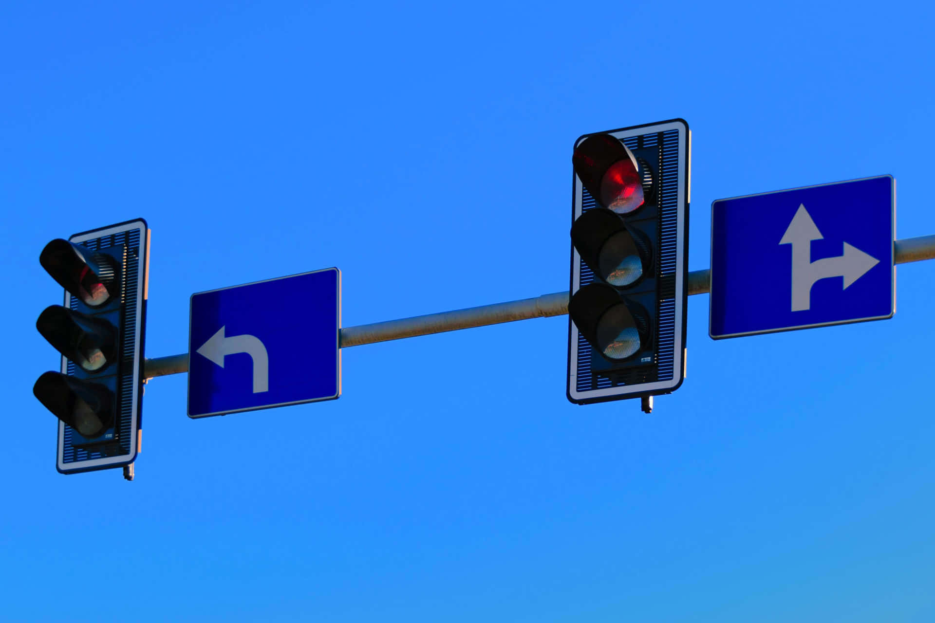 交通燈和轉彎標誌，背景是晴朗的藍天。