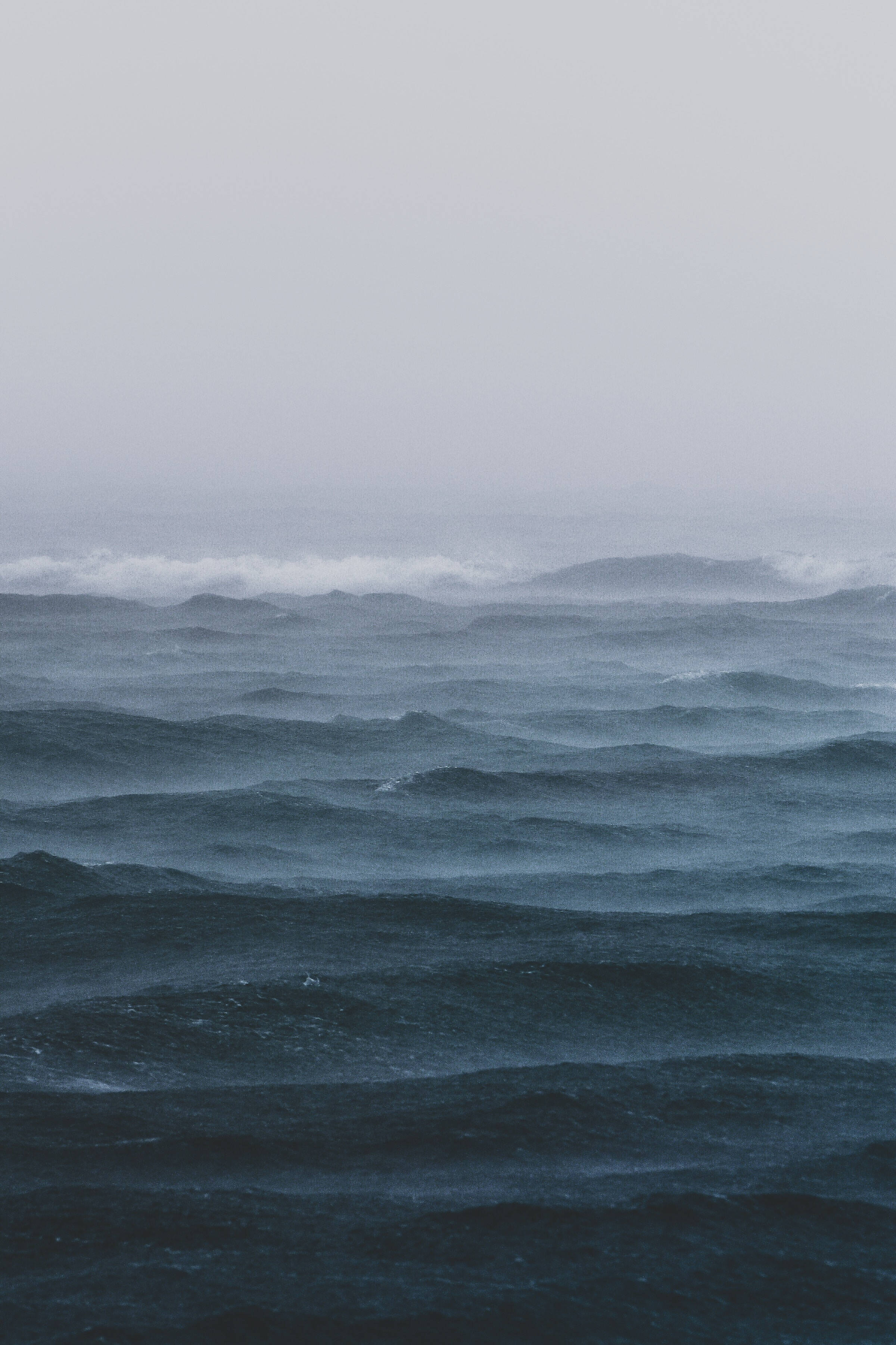 霧氣海浪暴風 壁紙 — 陰鬱的海洋，在陰沉的灰色天空下翻騰著深藍色的波浪。