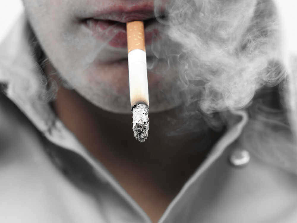 一個人吸煙，煙霧從點燃嘅一端升起。
