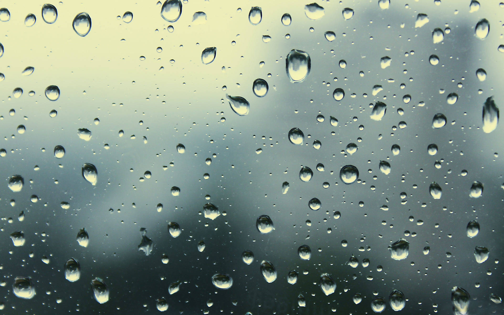 窗戶上的雨滴，背景是模糊的天空。