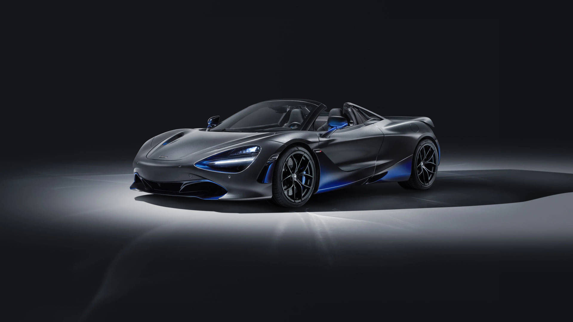 光滑的灰色McLaren 720S Spider，在黑暗的攝影棚環境中帶有藍色亮點。