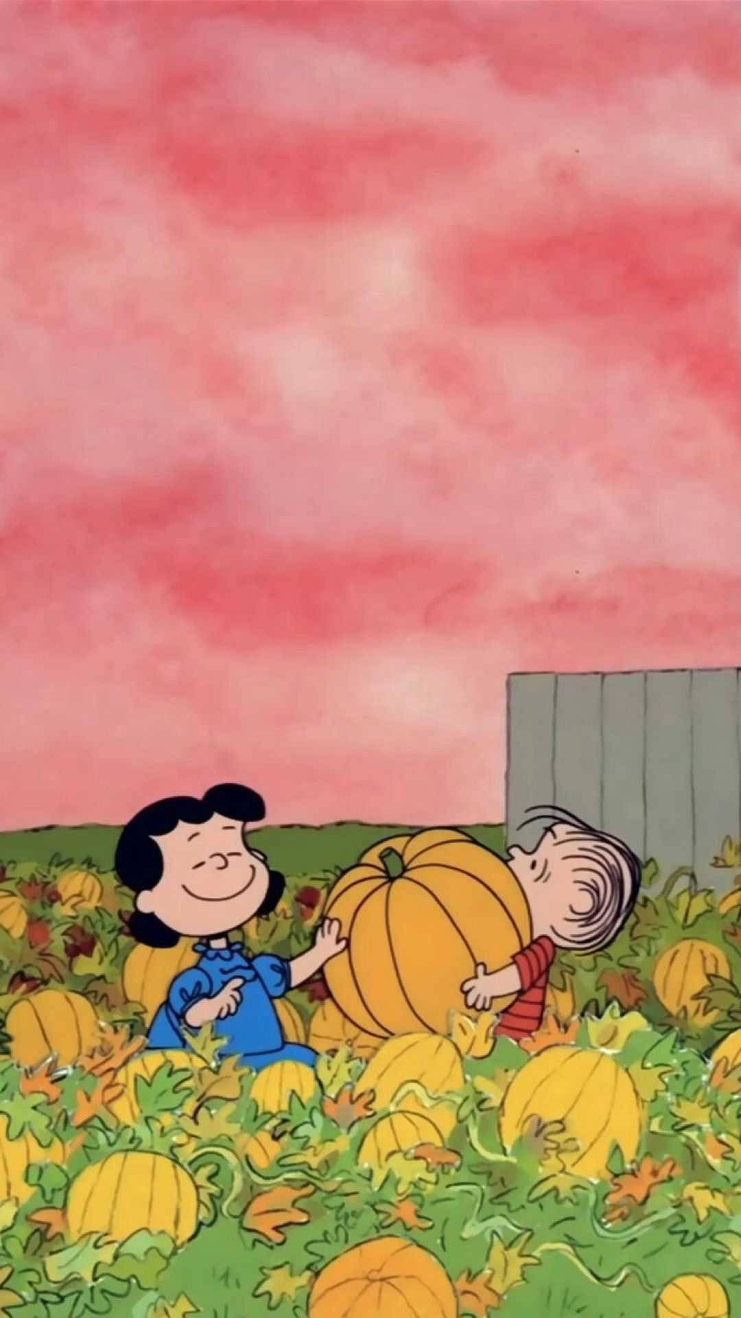 露西·凡·佩爾特與查理·布朗南瓜田 壁紙 — 兩個微笑的卡通小孩在粉紅色天空下，在充滿活力的秋田裡快樂地擁抱一個巨大的南瓜。