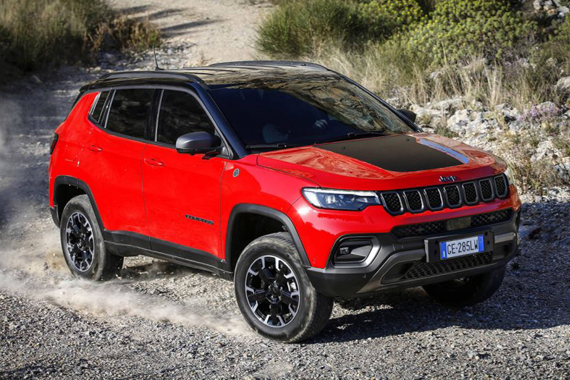 紅色Jeep Compass在碎石路上行駛，塵土飛揚
