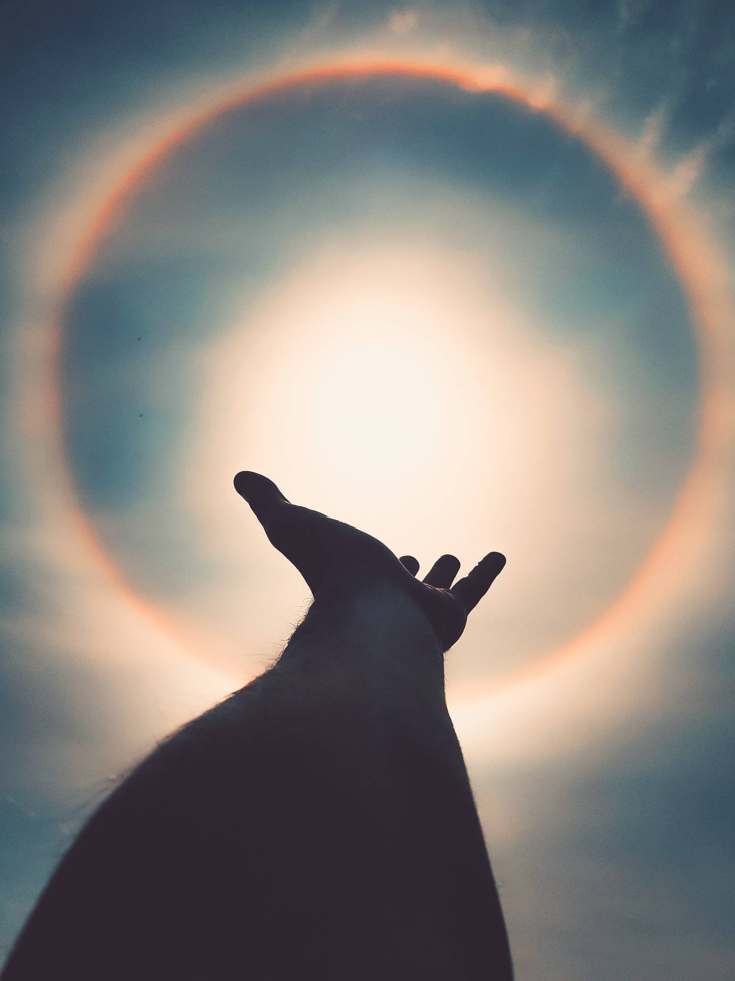 一隻手剪影伸向天空中發光的太陽日冕。