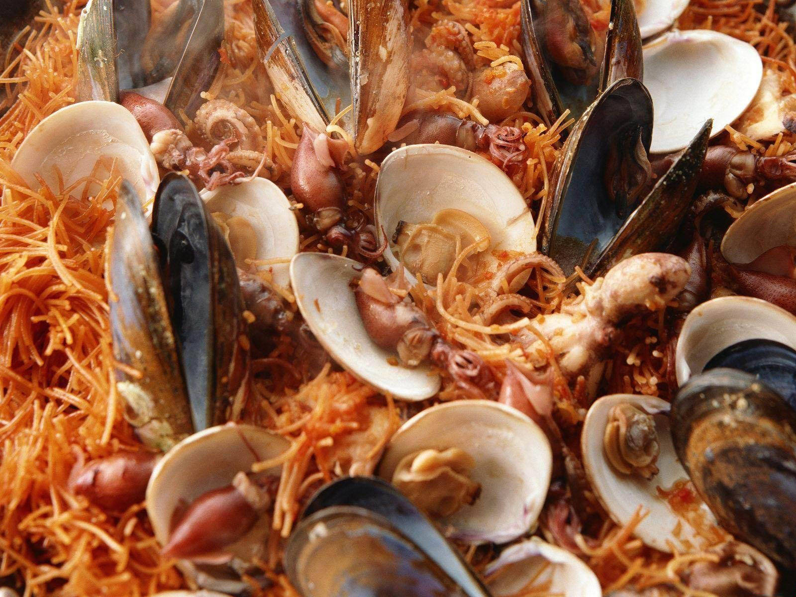 青口與蛤蜊炒麵 壁紙 — 一個充滿青口、蜆、魷魚和藏紅花飯的海鮮燉飯嘅鮮豔近鏡。