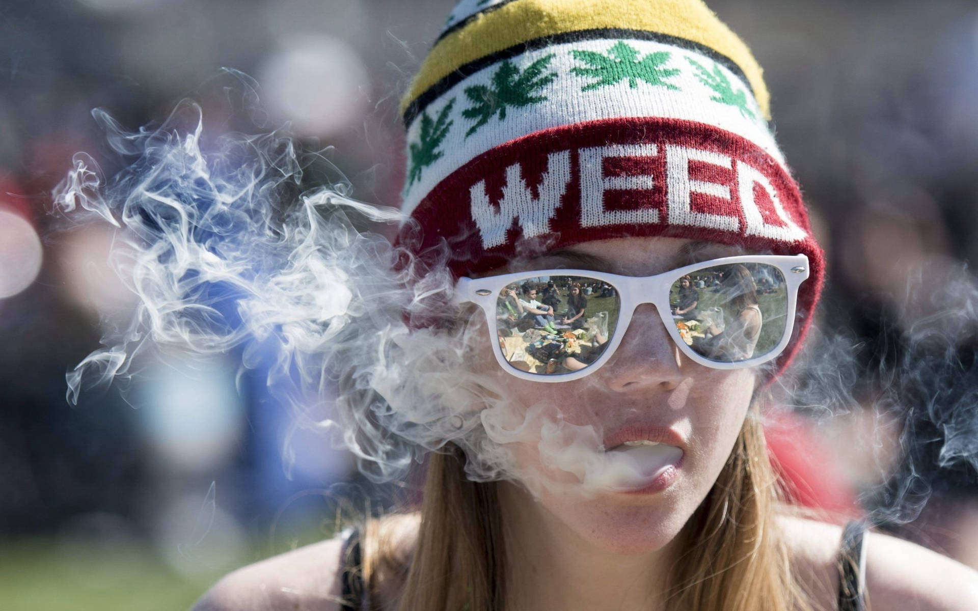 戴著weed冷帽和太陽眼鏡的人在戶外活動中呼出煙霧。