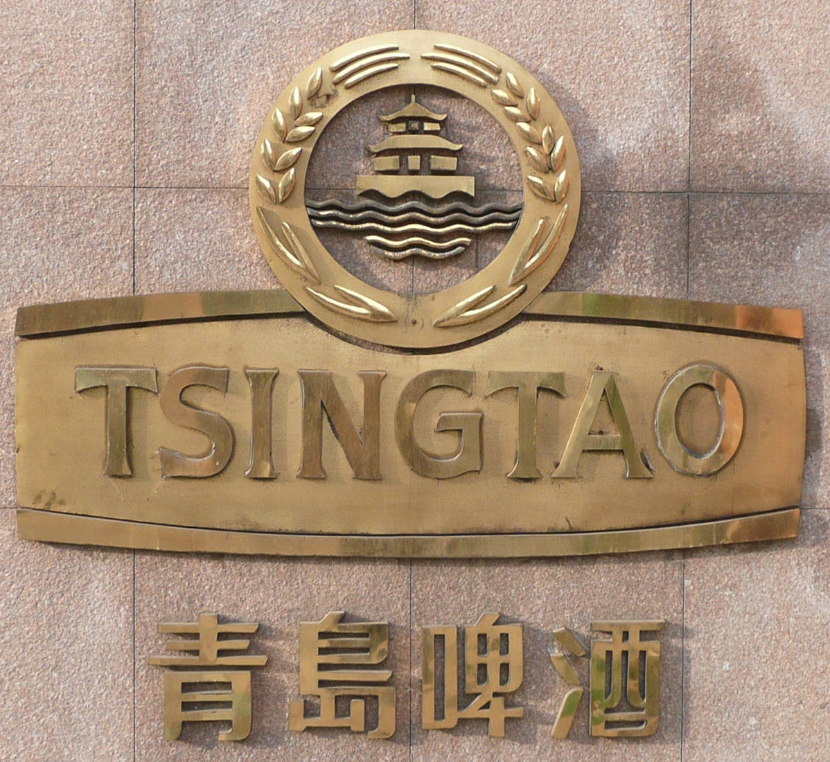 石牆上的金色青島啤酒標誌與寶塔徽章。
