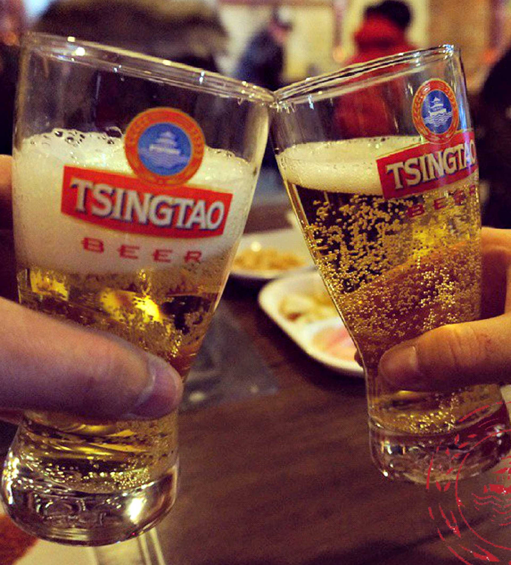 兩隻手喺昏暗嘅酒吧入面用青島啤酒杯敬酒。