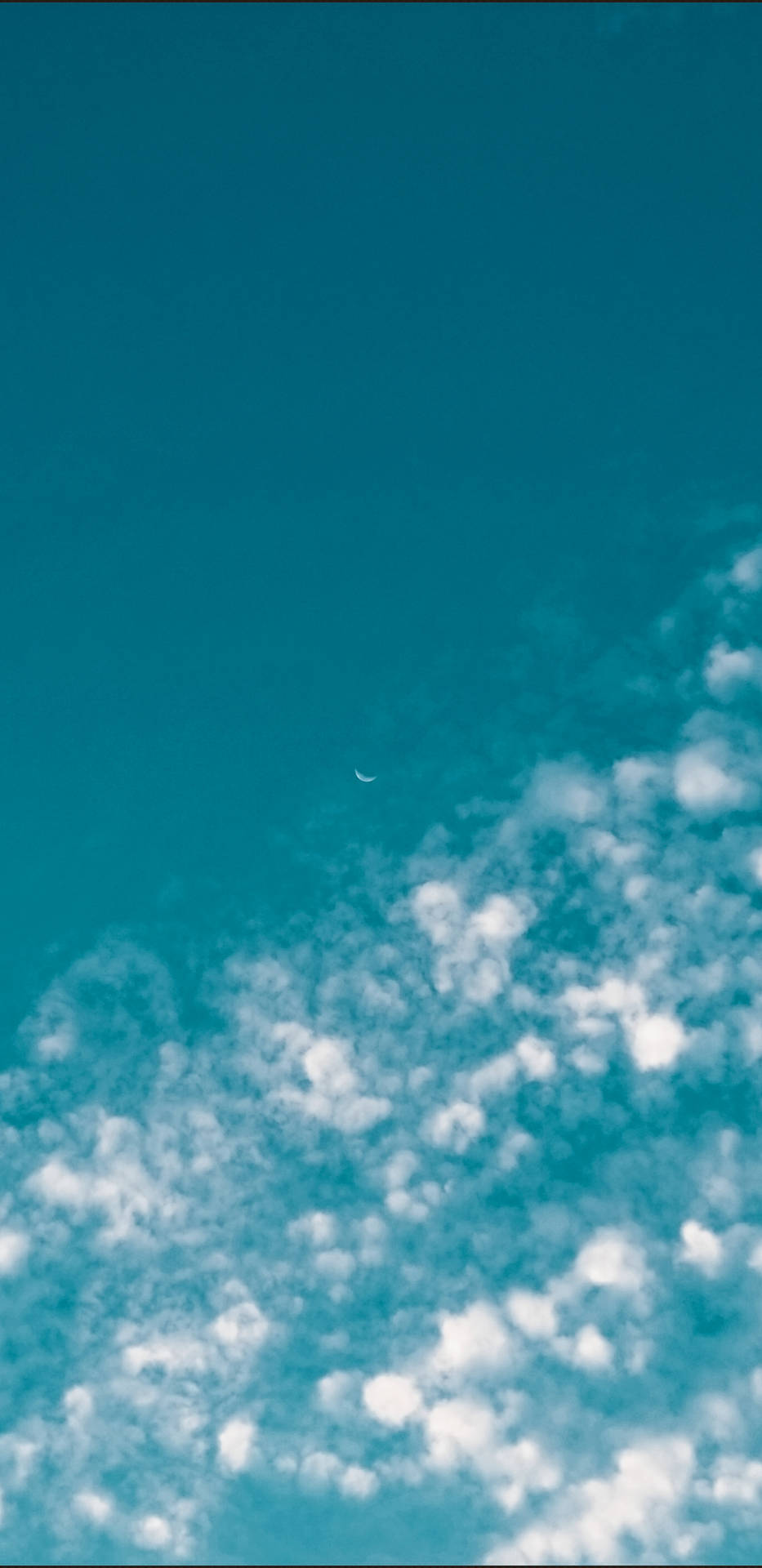 彎月位於蓬鬆白雲之上，背景為藍綠色天空