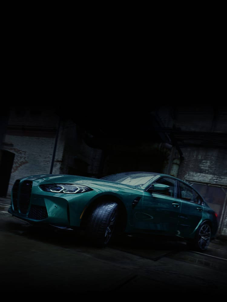 黑暗工業車庫中帶有戲劇性燈光的藍綠色BMW M3。