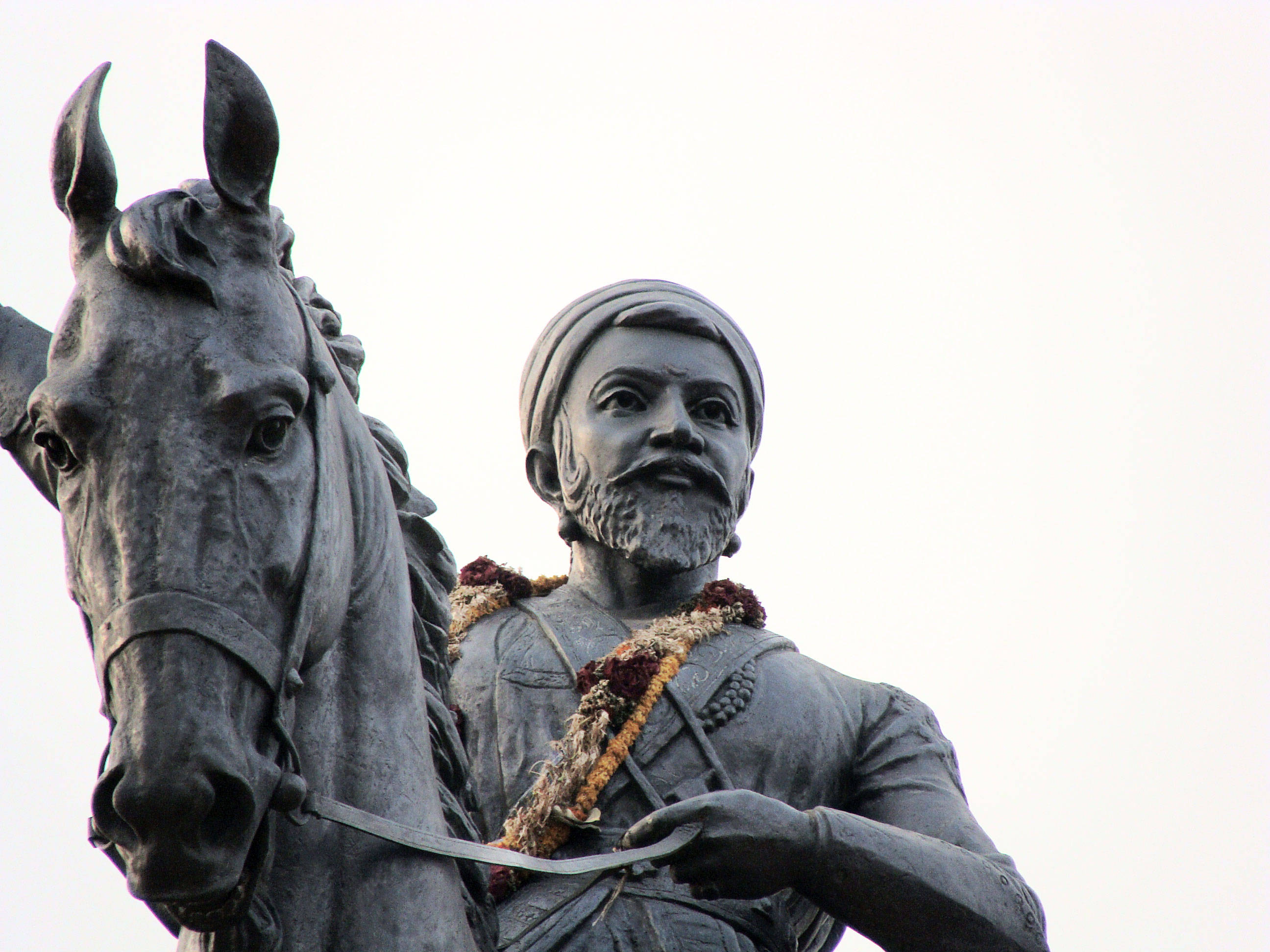 Indian 桌布 壁紙 — 青銅騎馬雕像特寫，一位留鬍鬚、戴頭巾的男子手持韁繩，肩上披著花環。