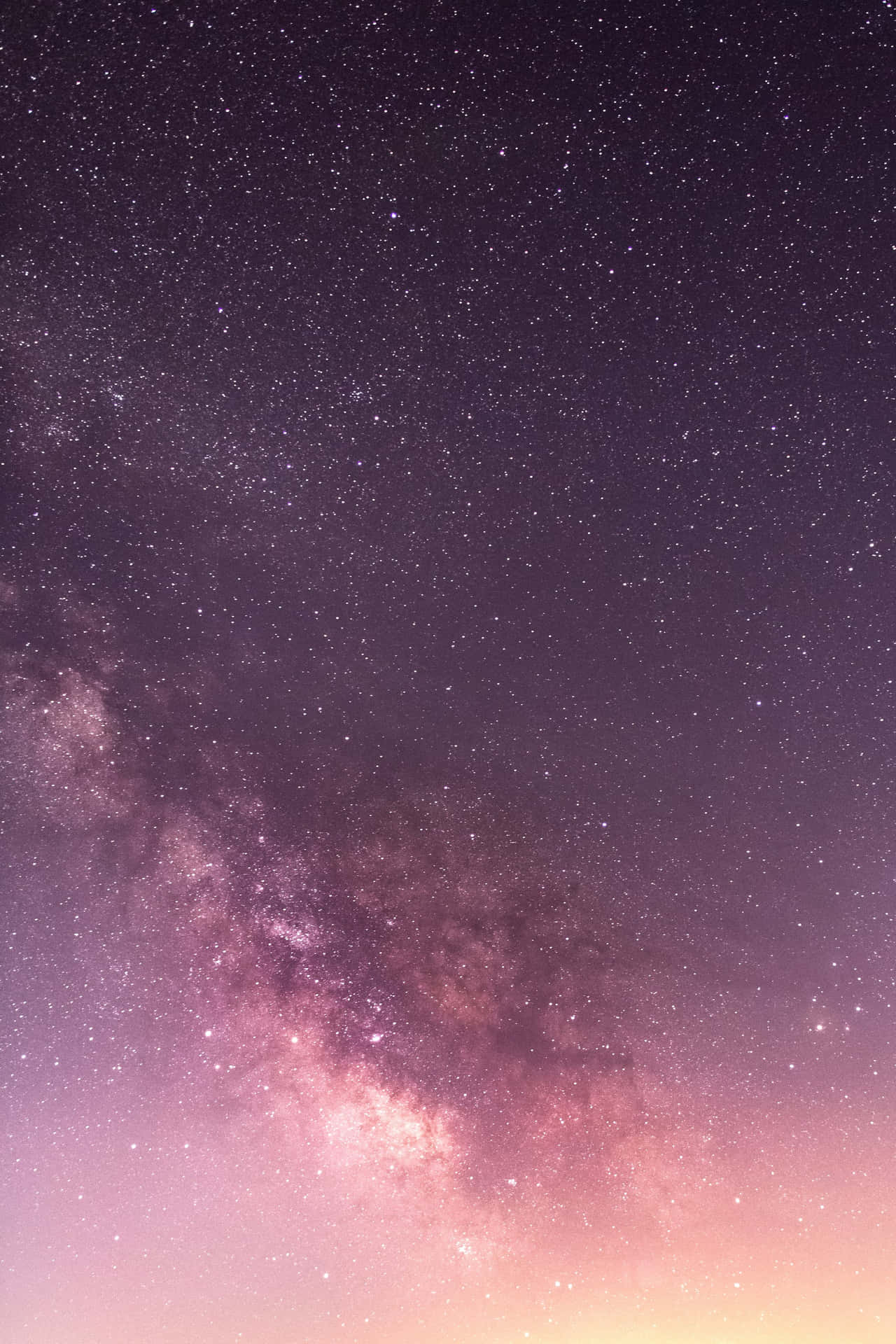 銀河系在繁星點點的夜空中散發出紫色和粉紅色的色調。