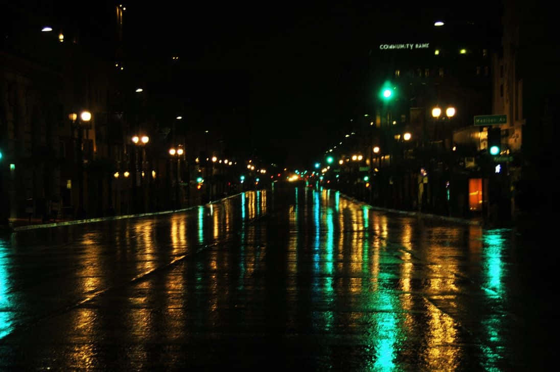 夜晚城市街道上的雨，帶有街燈和招牌的發光倒影。