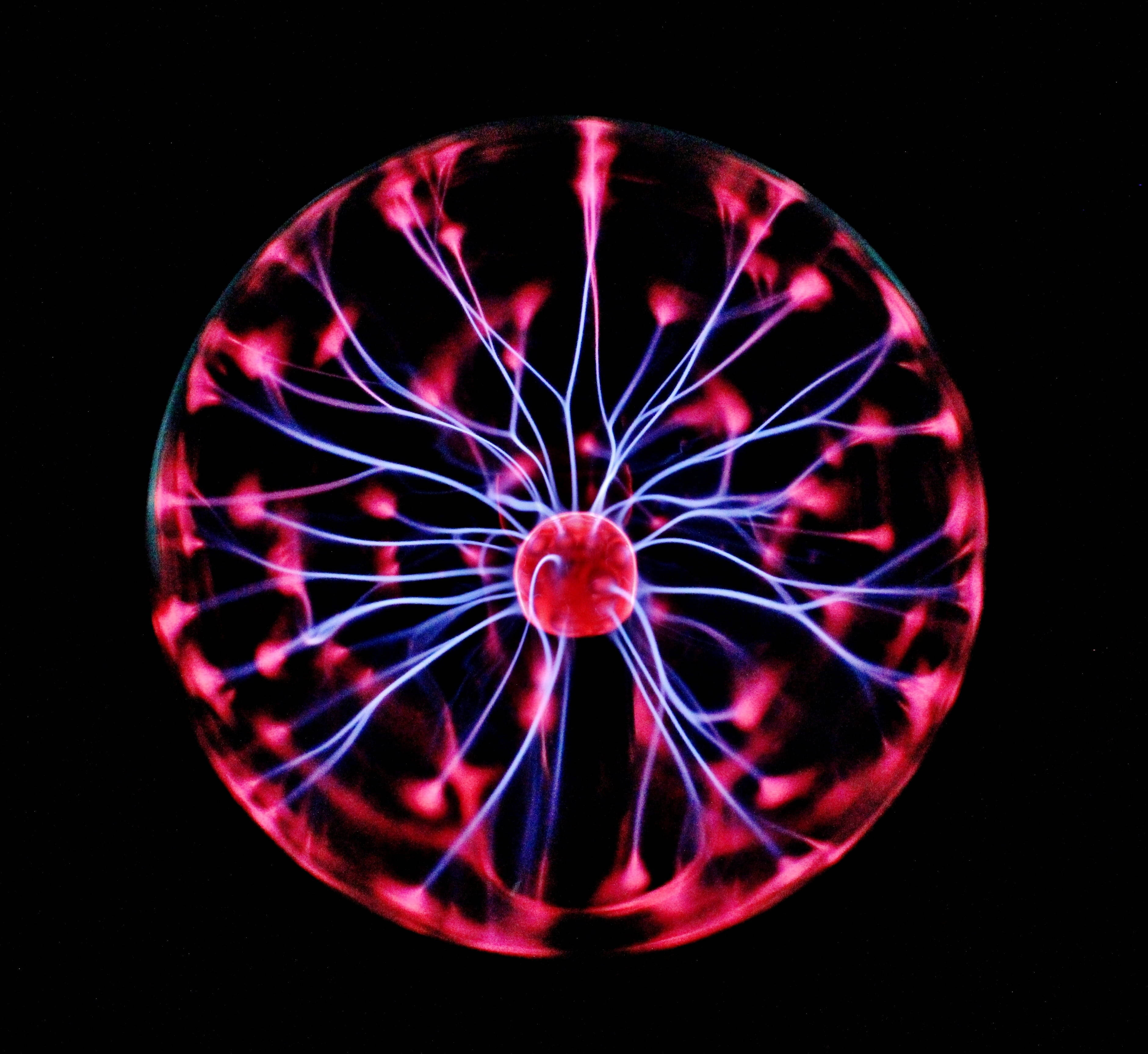靜態霓虹電球 壁紙 — 一個發光的等離子球體在黑色背景下發出鮮豔的粉紅色和藍色電絲。