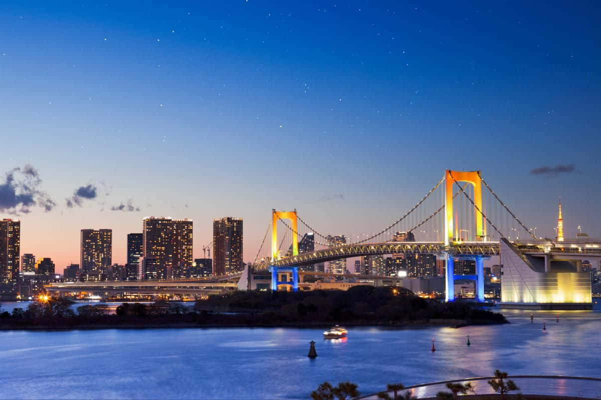 靜止欣賞東京彩虹橋的迷人之美 壁紙 — 東京的彩虹橋在水面上閃爍著鮮豔的光芒，映襯著繁星點點的暮色天空。