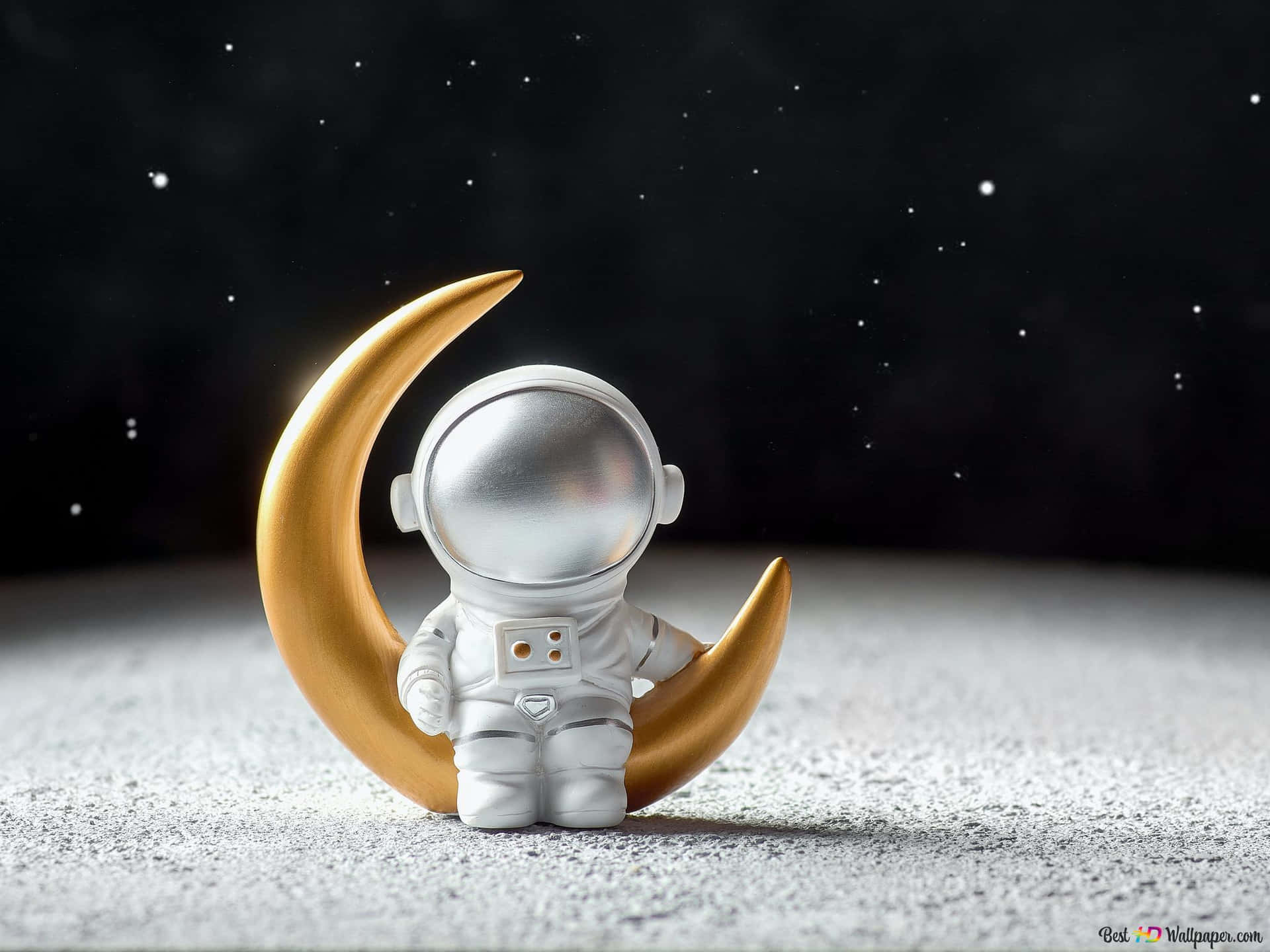 在星空下，金色新月旁邊的小太空人公仔。