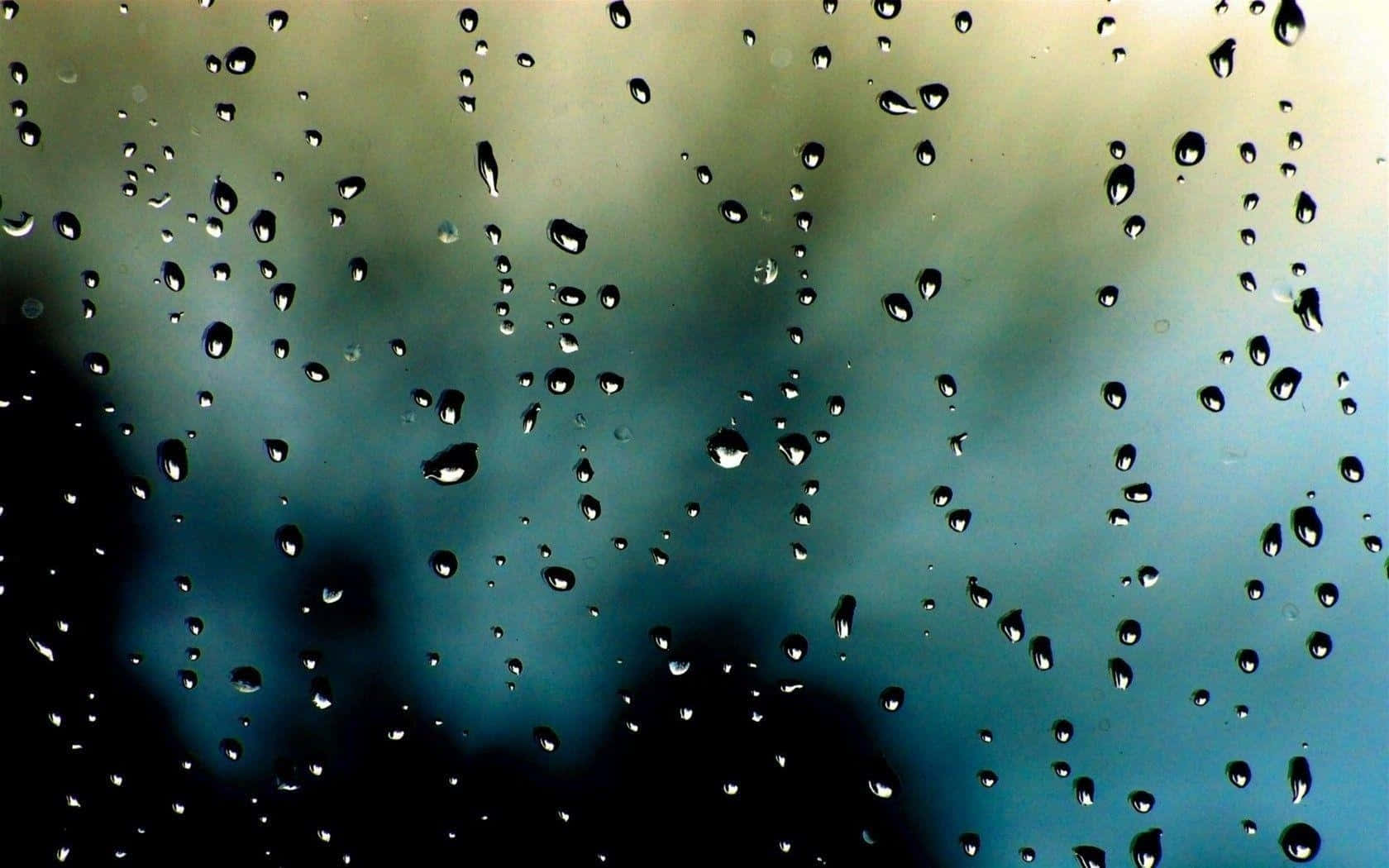 窗戶上的雨滴，背景是模糊的藍綠色天空。