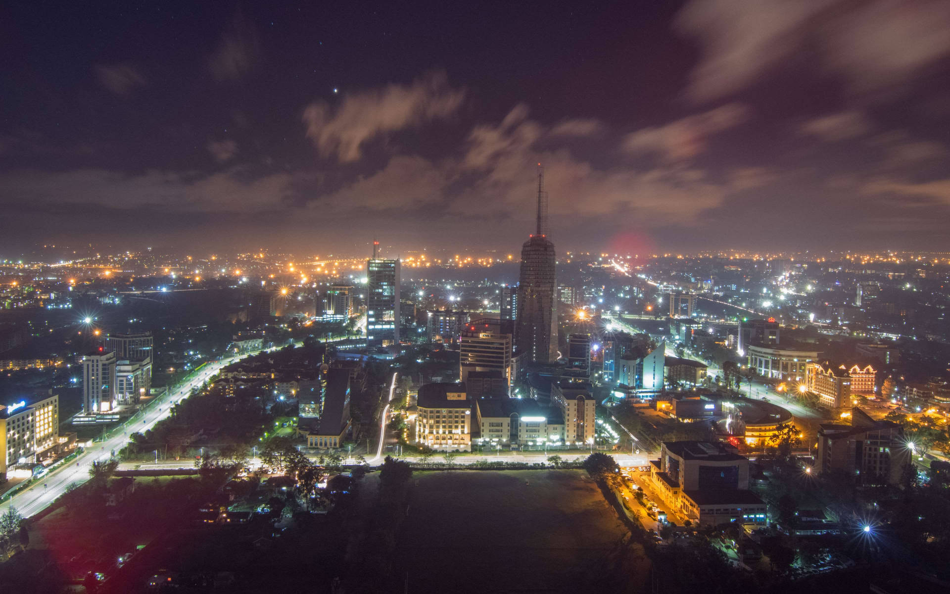 星空下，高樓大廈和發光的街道照亮城市的夜間航拍圖。