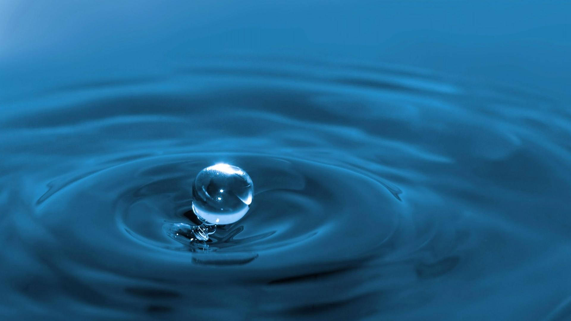 懸浮的水滴在平靜的藍色水面上產生漣漪。