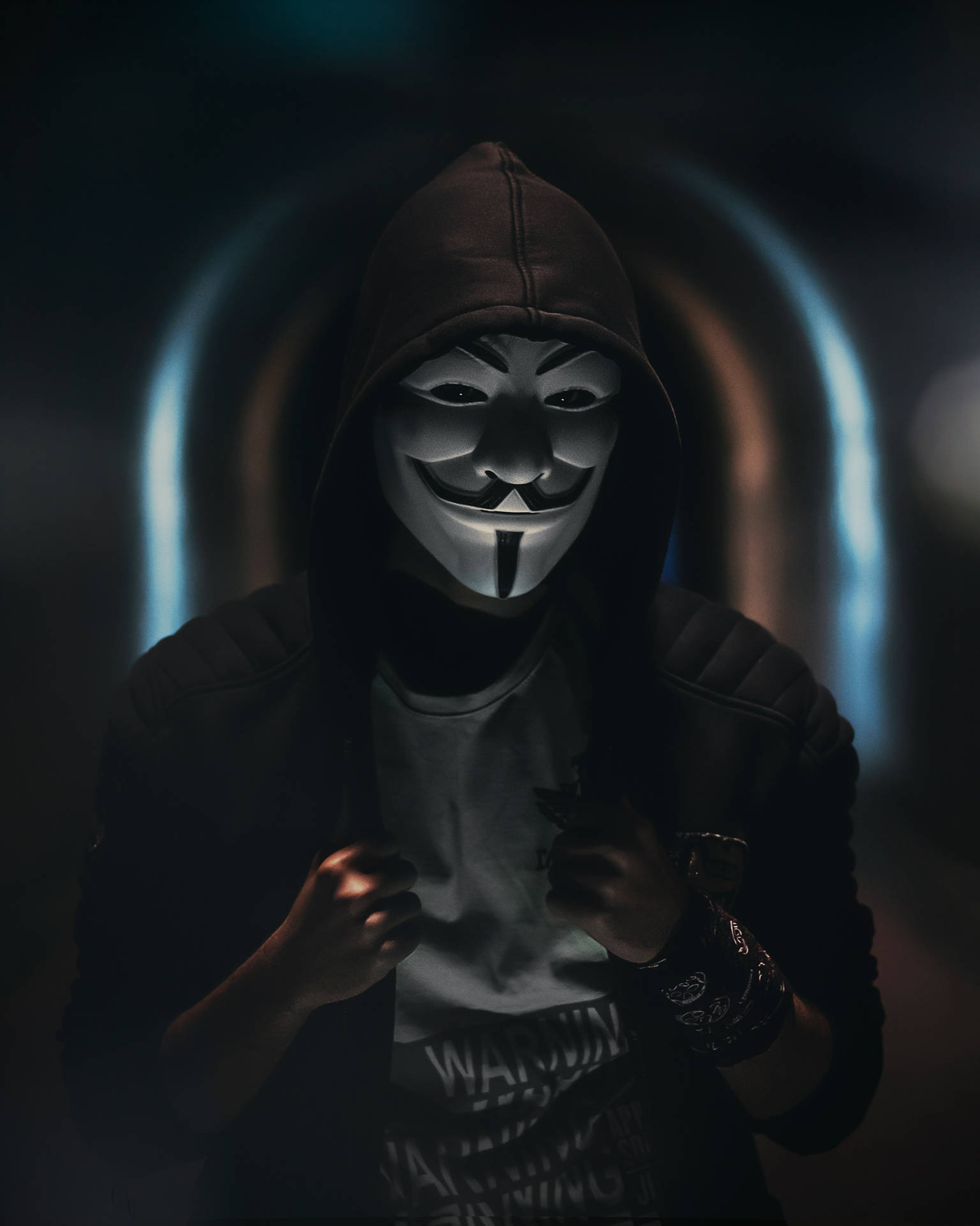 在黑暗隧道中戴著蓋伊·福克斯面具的人，身後有藍色發光拱門。