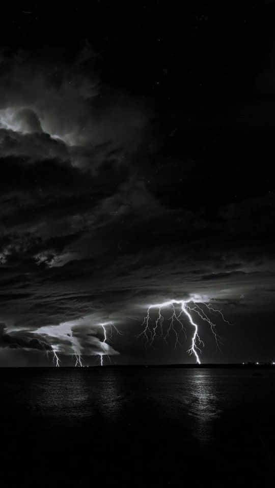 夜晚暴風雲下，黑暗水面上閃電擊中。