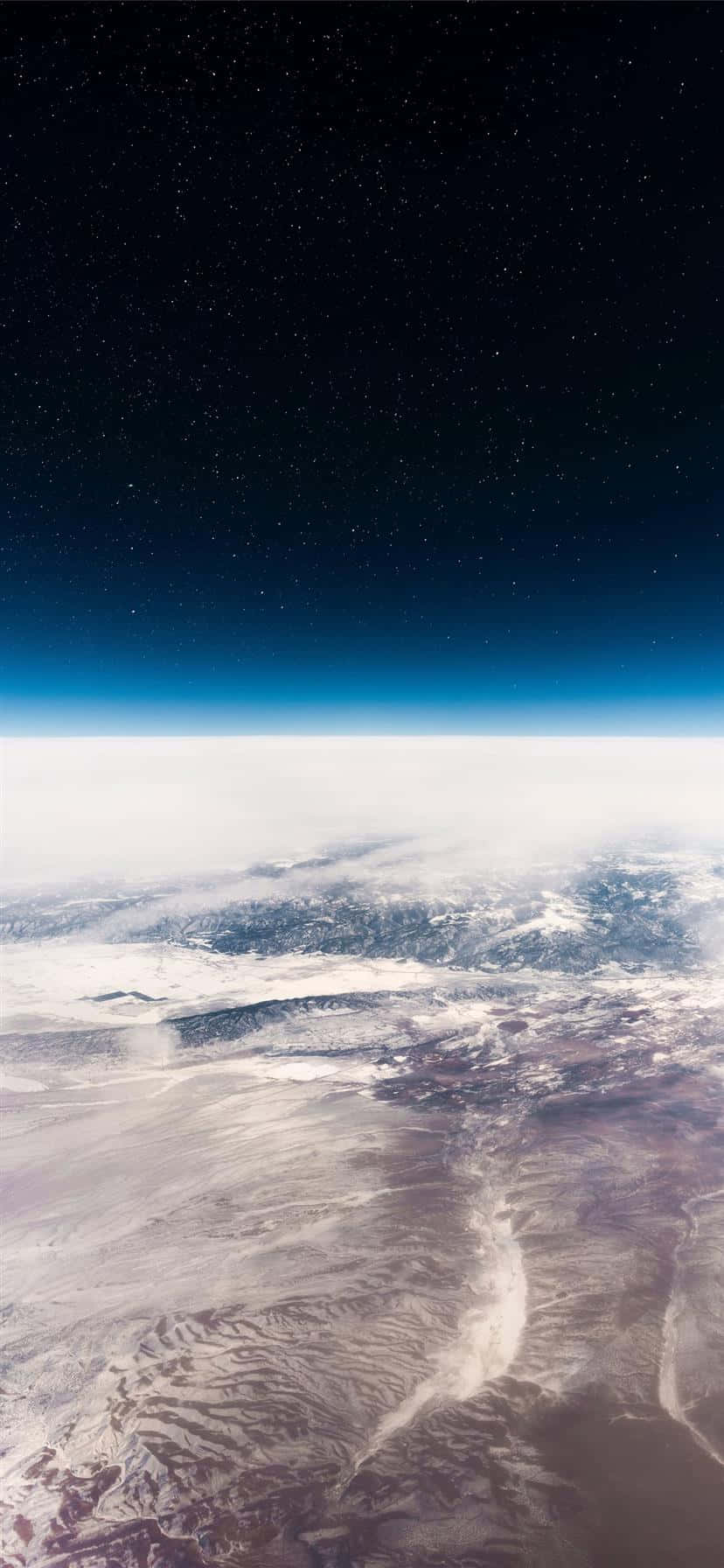 革命性iPhone 11，尖端科技 壁紙 — 從太空俯瞰地球的壯麗景色，展現了白雪覆蓋的山脈地形上方的星空夜空。
